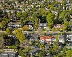 Aerial view of a suburban neighborhood with houses surrounded by trees and greenery.