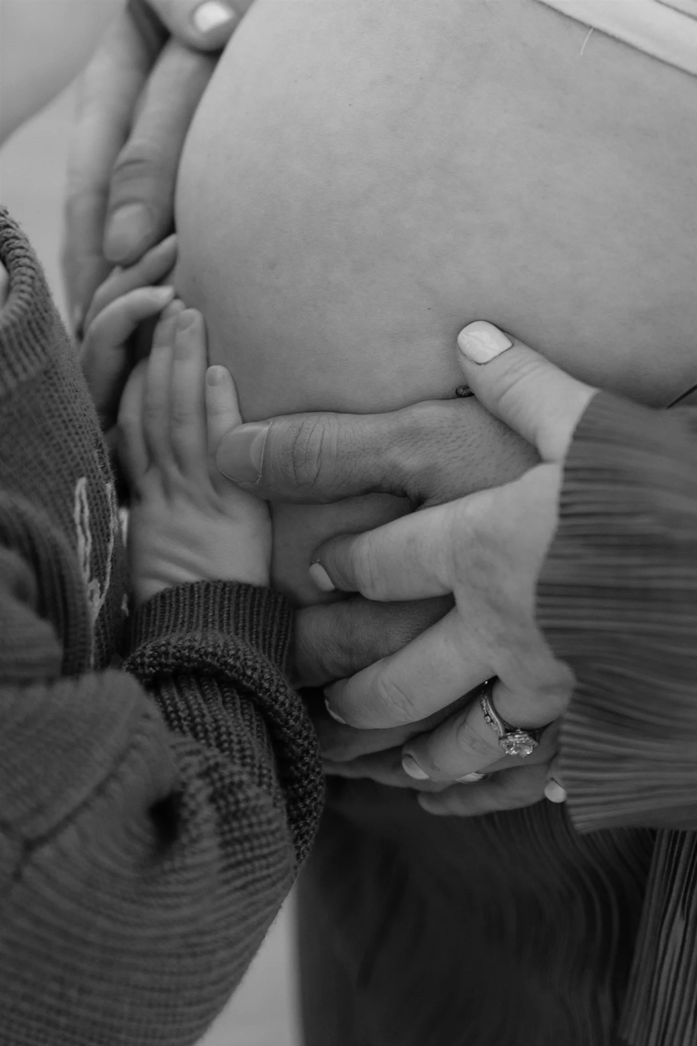 Close-up of hands gently holding a pregnant woman's belly.