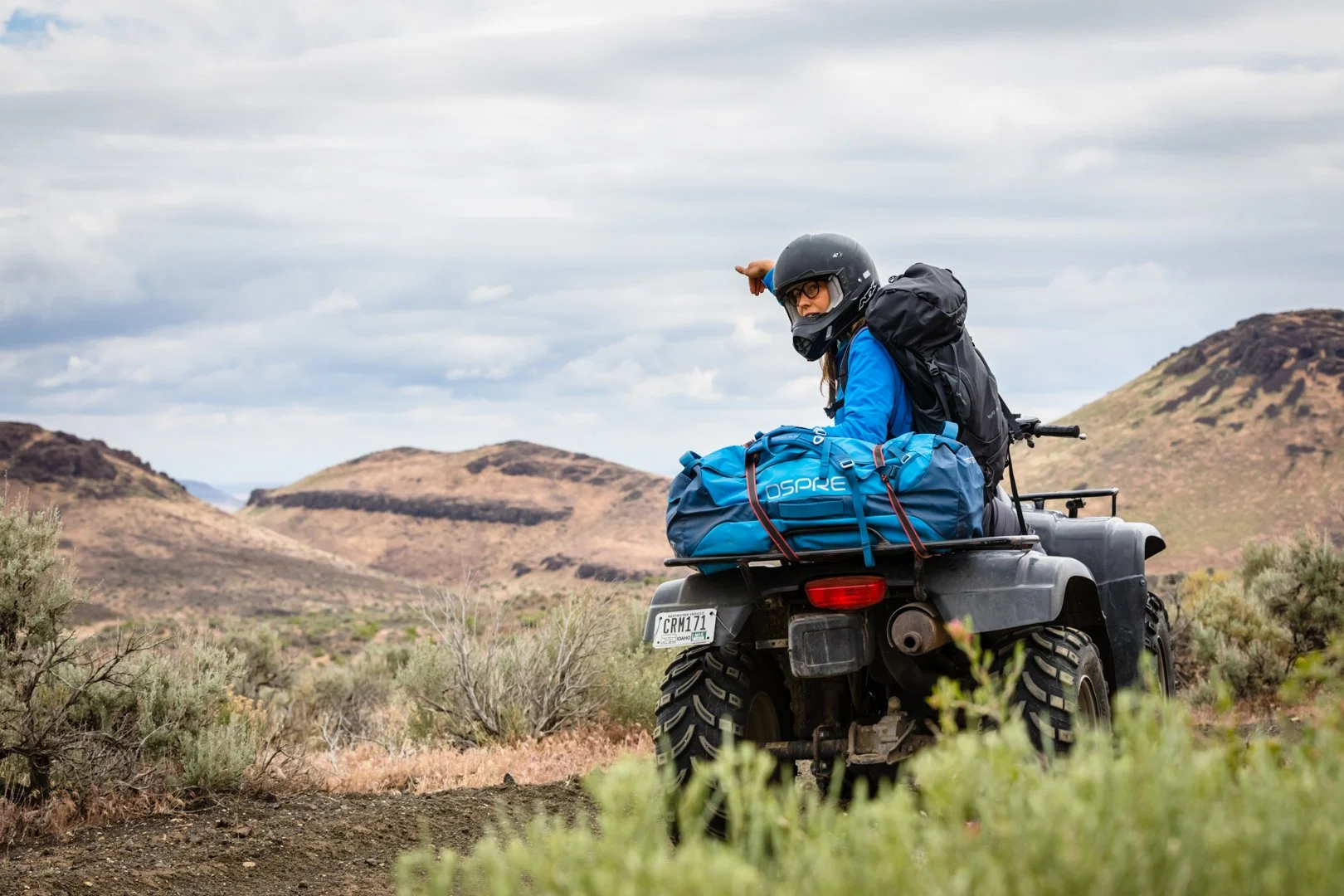 Caitlin Davis on a quad pointing to the location of a golden eagle nest during filming of the Golden project, photographed by Fieldborn Creative.