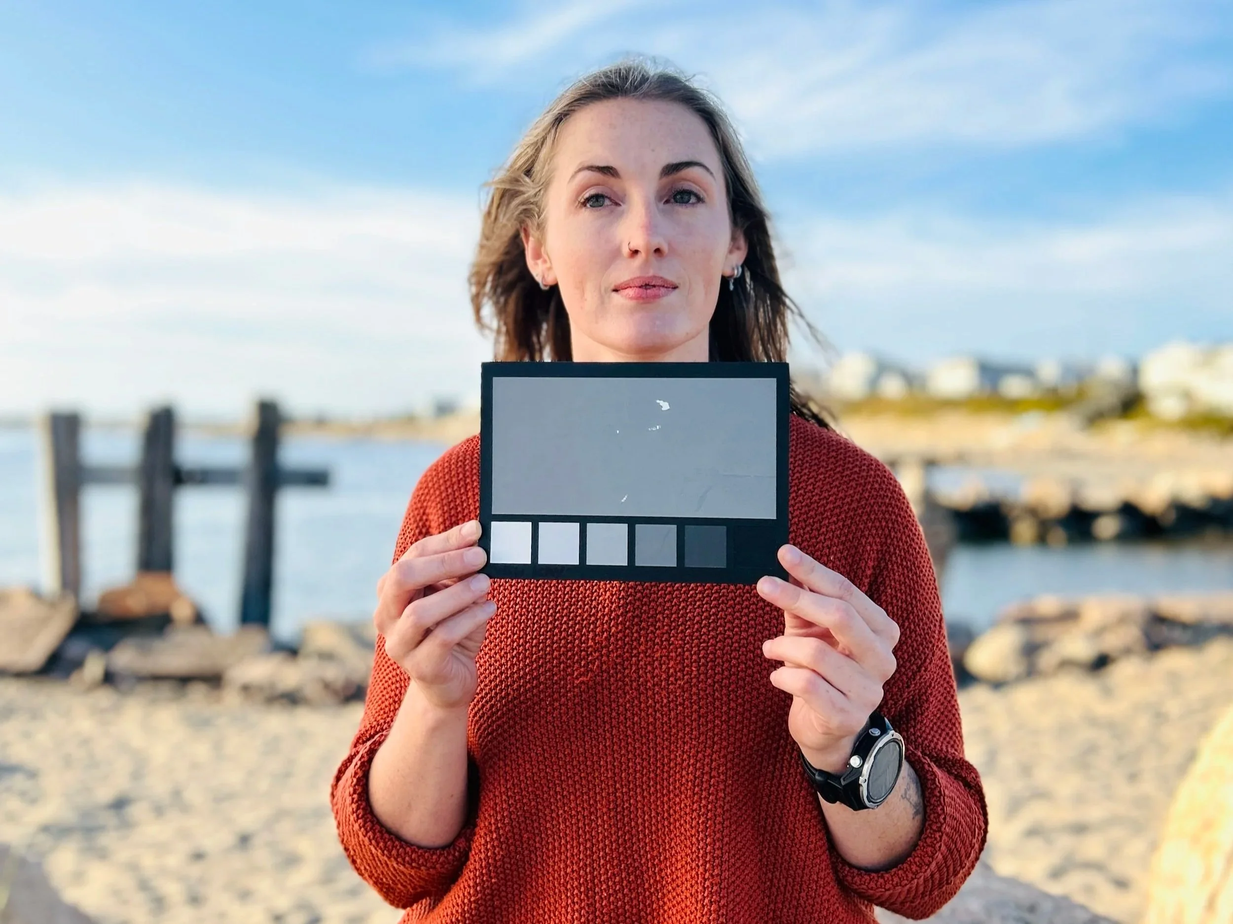 Behind-the-scenes photo of a production crew member holding a white balance card in the field during an interview setup, photographed by Fieldborn Creative.