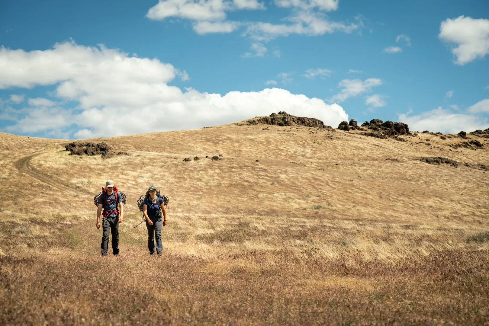 Caitlin Davis and a co-researcher walking back from the field in the Owyhee Canyonlands after a golden eagle study, captured with a wide-angle lens for the Golden film, photographed by Fieldborn Creative.