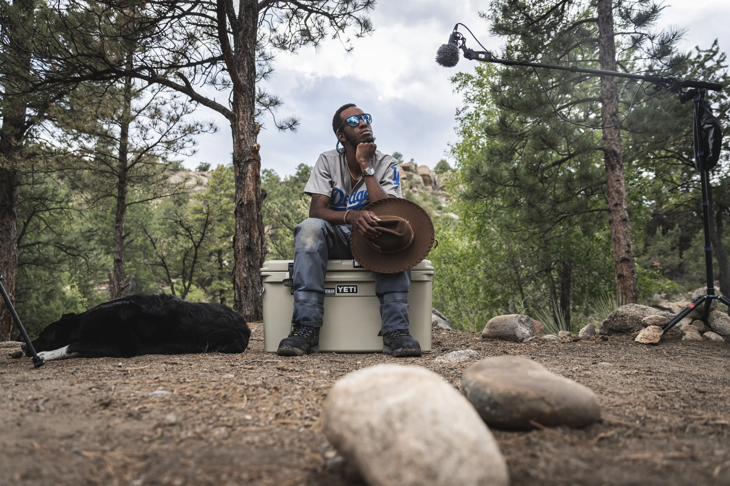 Eeland Stribling sitting on a cooler during an interview in a Colorado forest while shooting the Punchline film, produced by Fieldborn Creative.