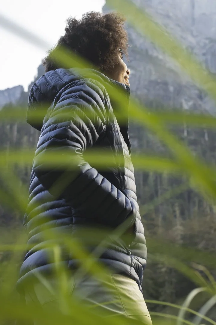 Woman on a backpacking trip in the mountains of Washington State, wearing a puffy jacket, photographed on assignment for Stio by Fieldborn Creative.