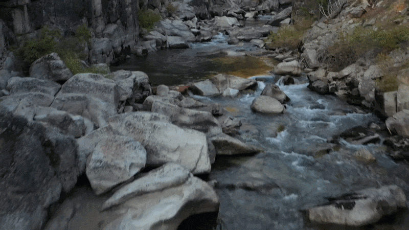 A rocky mountain stream flowing through a rugged landscape with rocks and vegetation. Commercial lifestyle production by Fieldborn Creative.