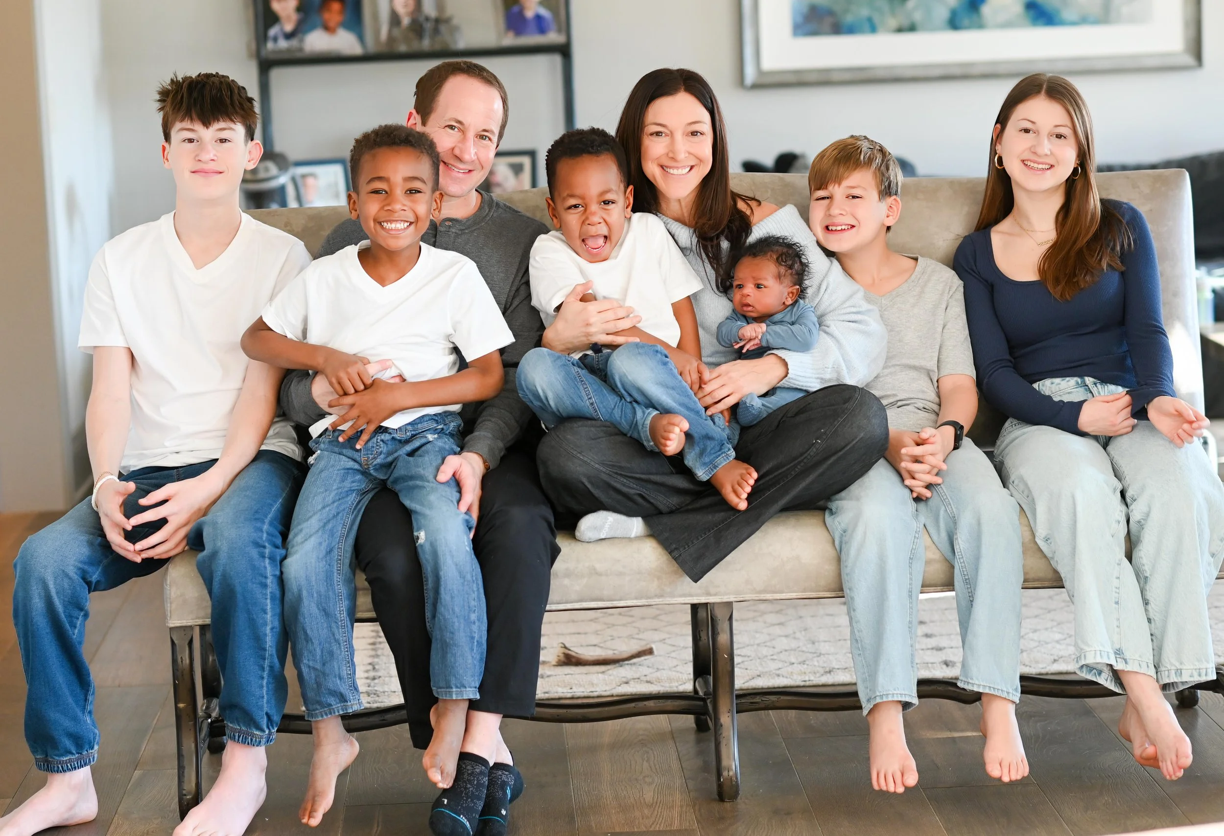 A multi-generational family sitting on a sofa in a living room, smiling and enjoying each other's company.