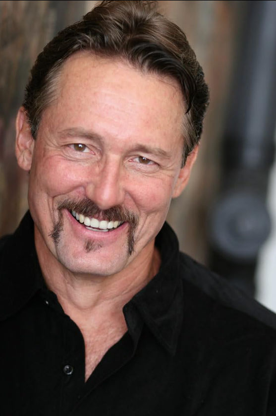 Actor, Director, Fight Coordinator & Weapons Expert Anthony De Longis smiling in a black collared shirt.