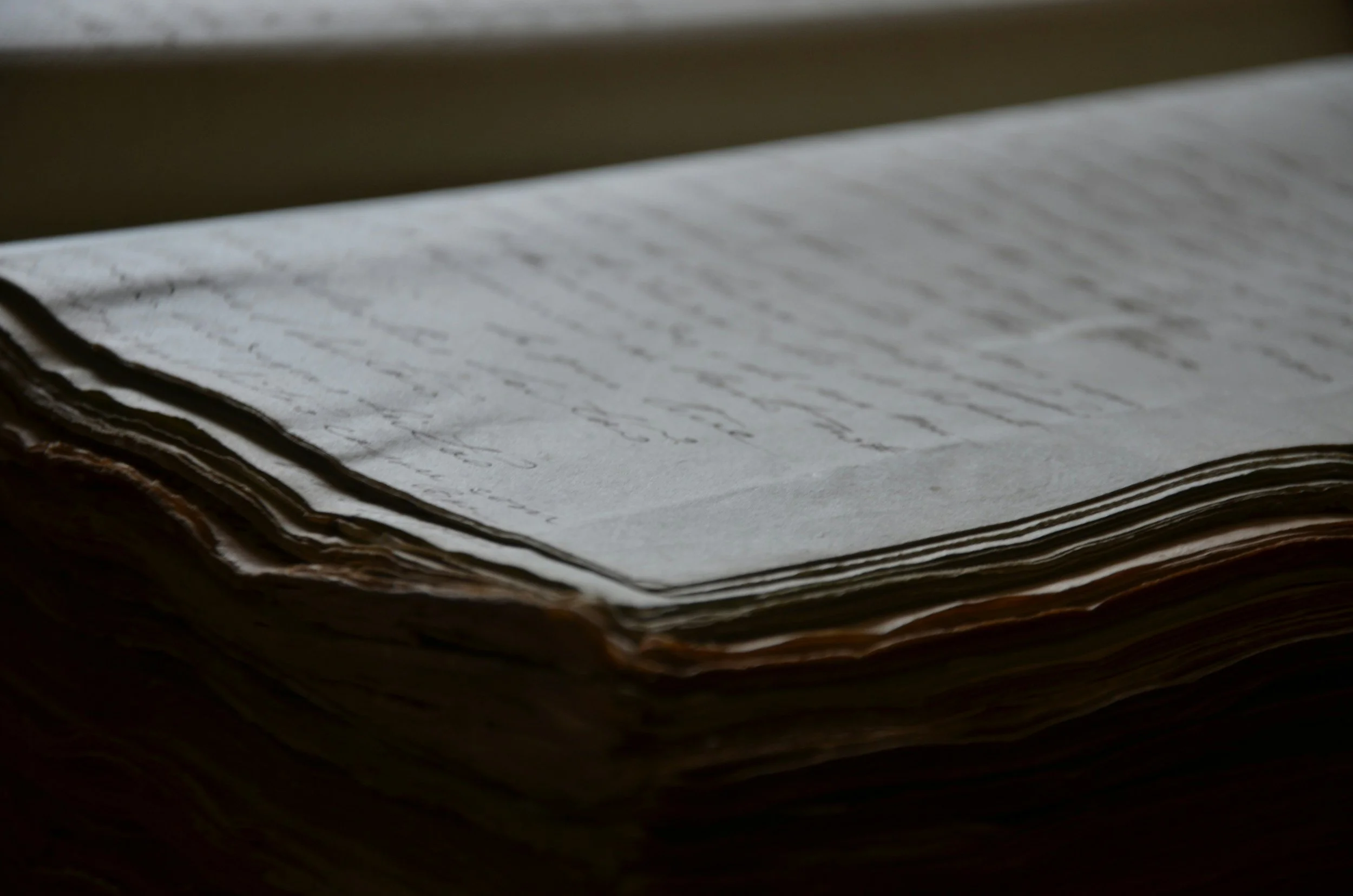Close-up of an open, old, handwritten journal or letter with yellowed, slightly curled pages.