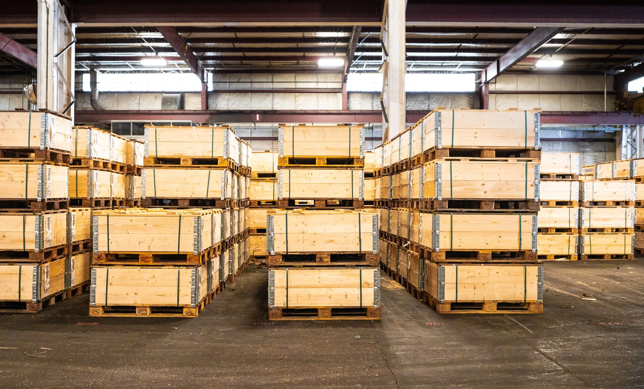 Stacks of wooden crates on pallets inside a warehouse.