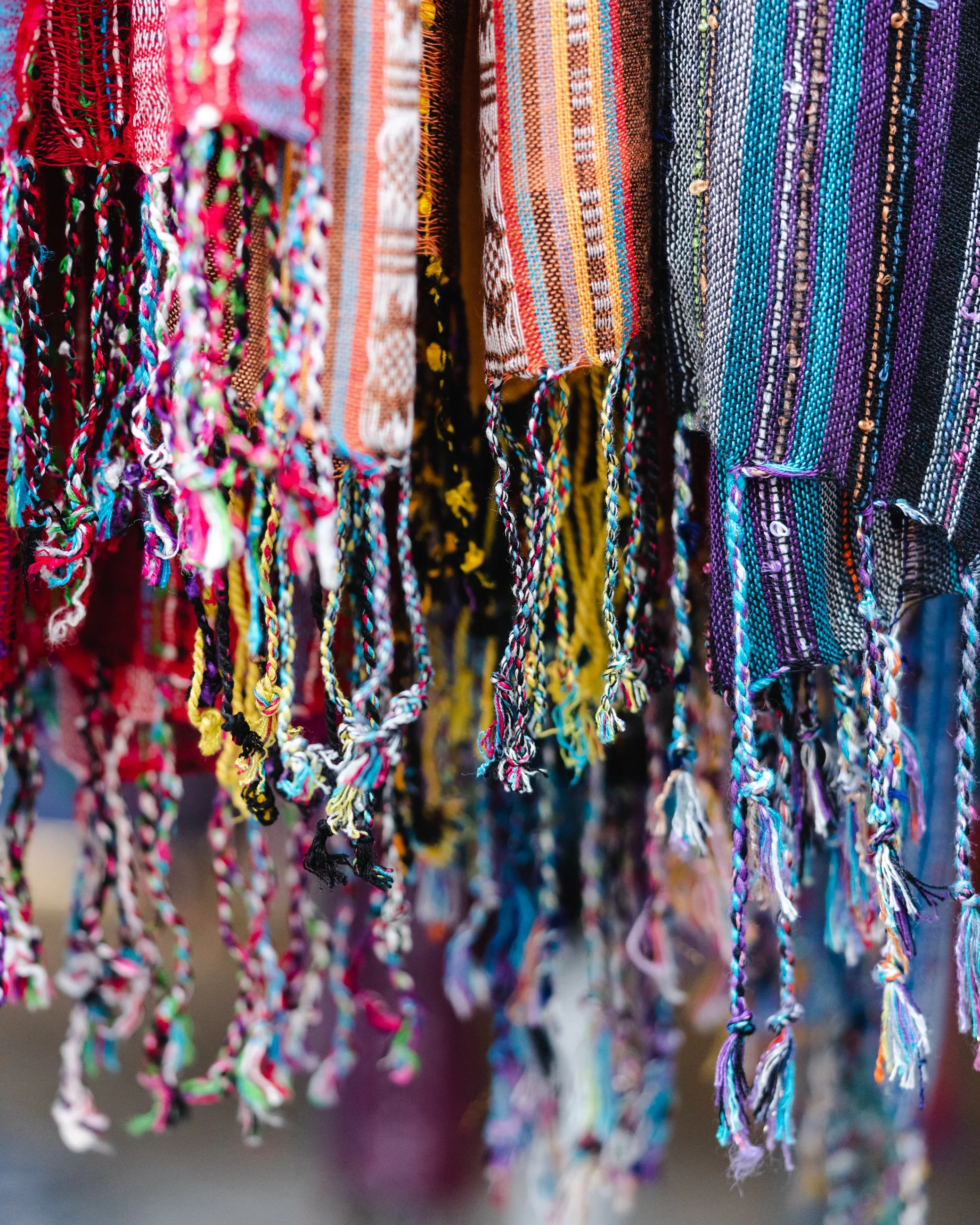 Colorful woven fabrics with fringed edges hanging together.