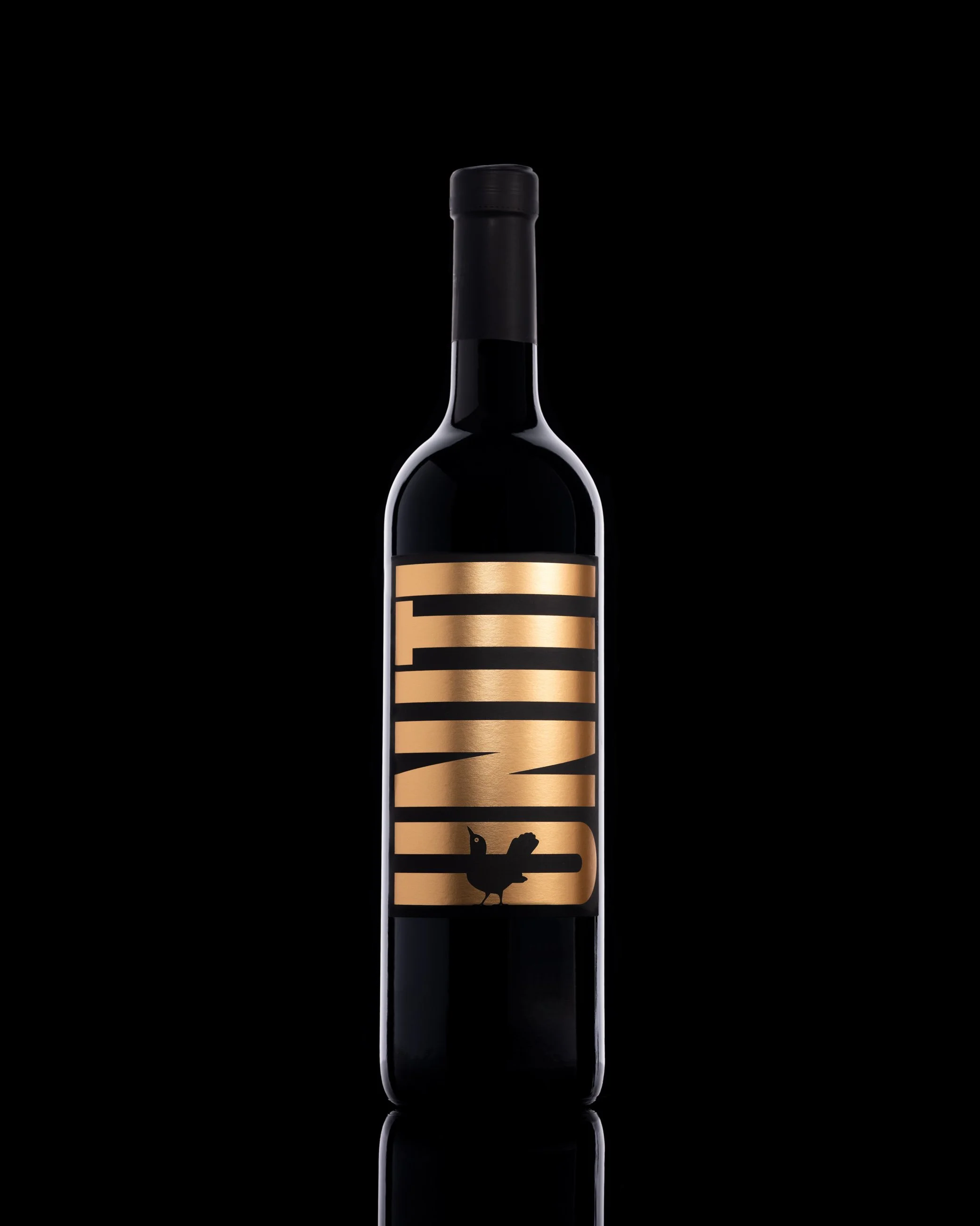 Black wine bottle product photography with gold label and minimal dark background