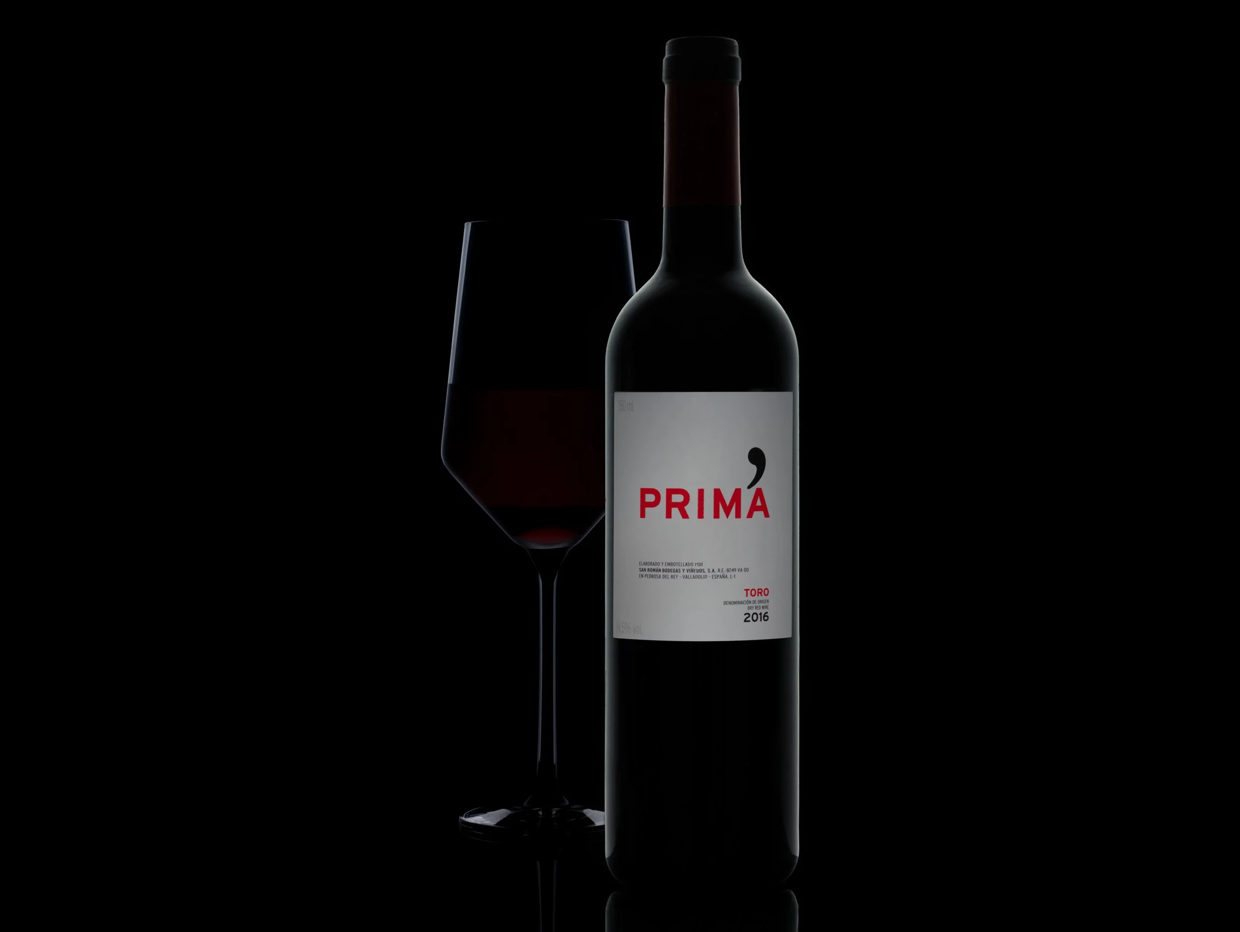 Red wine bottle still life photography with glass and dark studio lighting