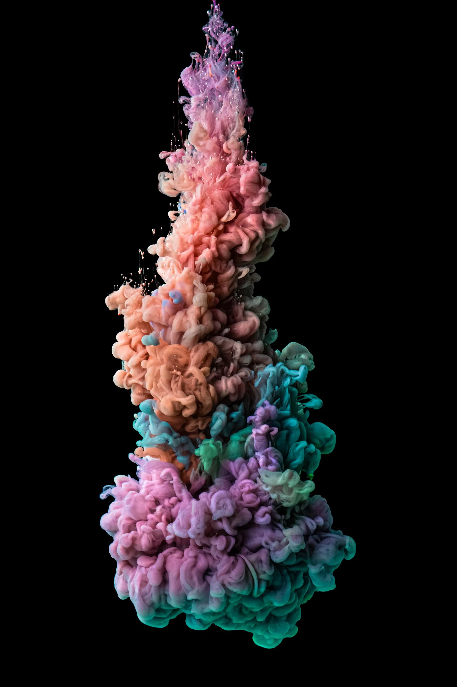 Colorful ink cloud dispersing in black water, forming abstract shapes.
