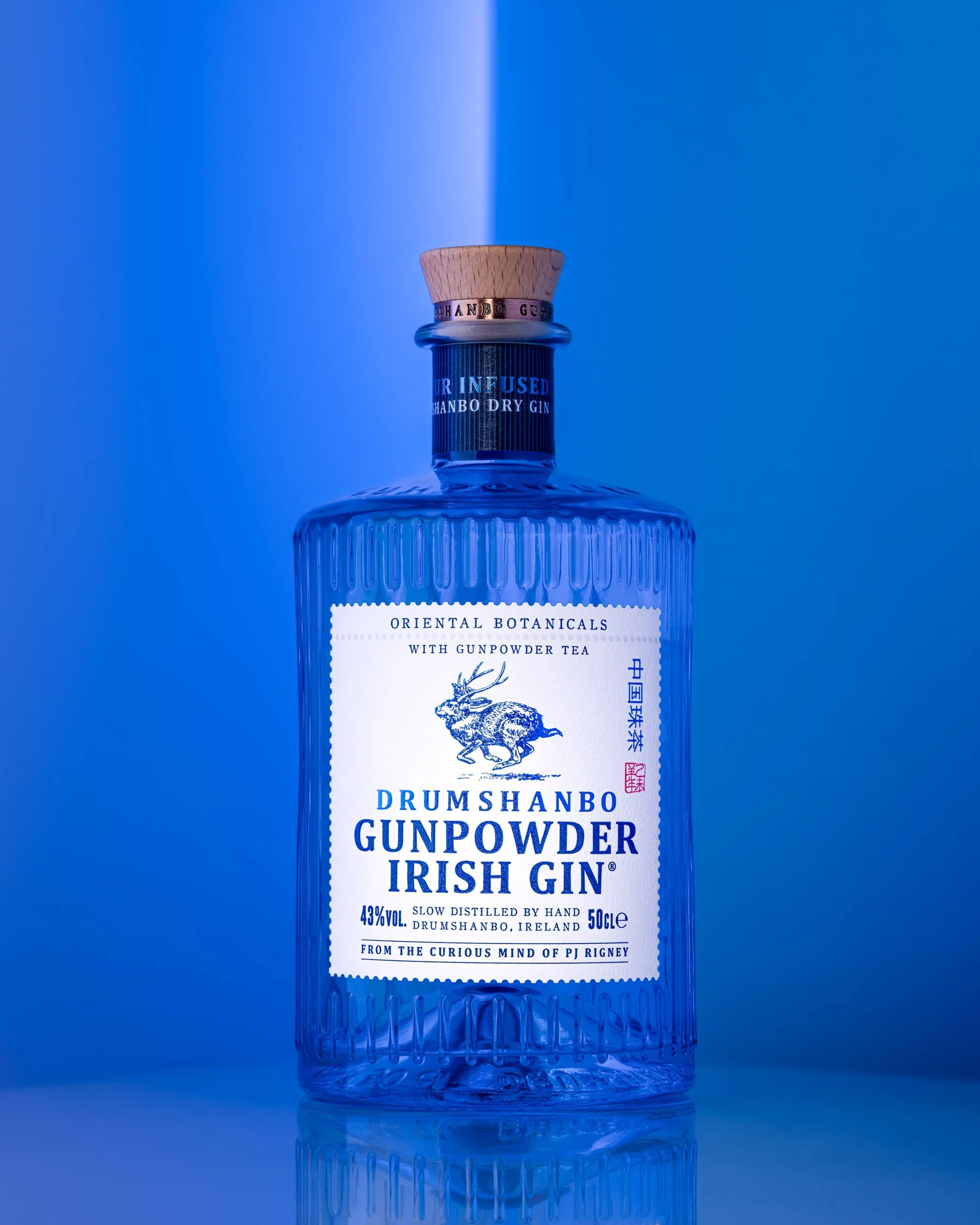 Blue gin bottle product photography with gradient blue background and studio lighting