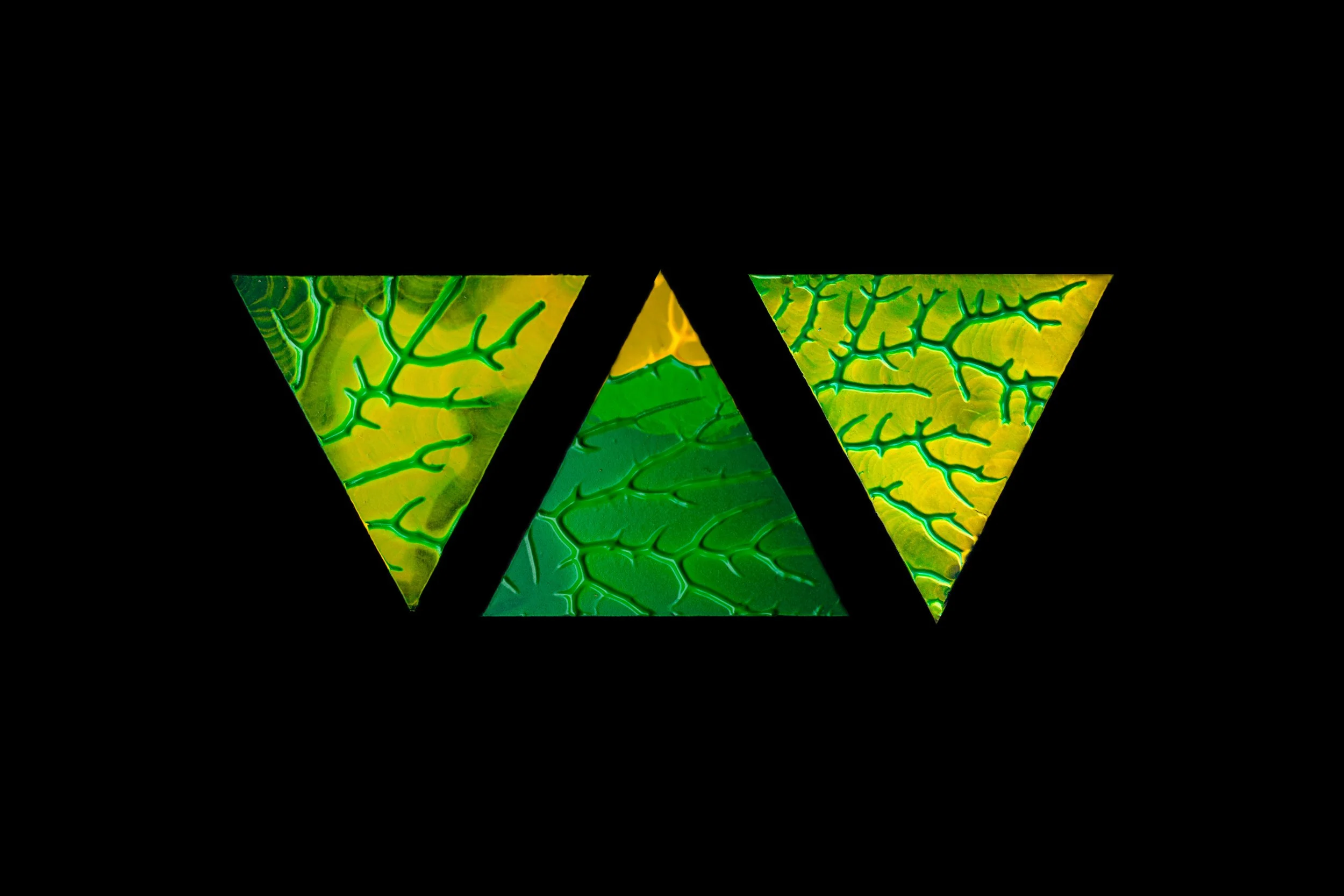 Colorful abstract pattern of green and yellow leaf-like textures with black geometric shapes overlaying.