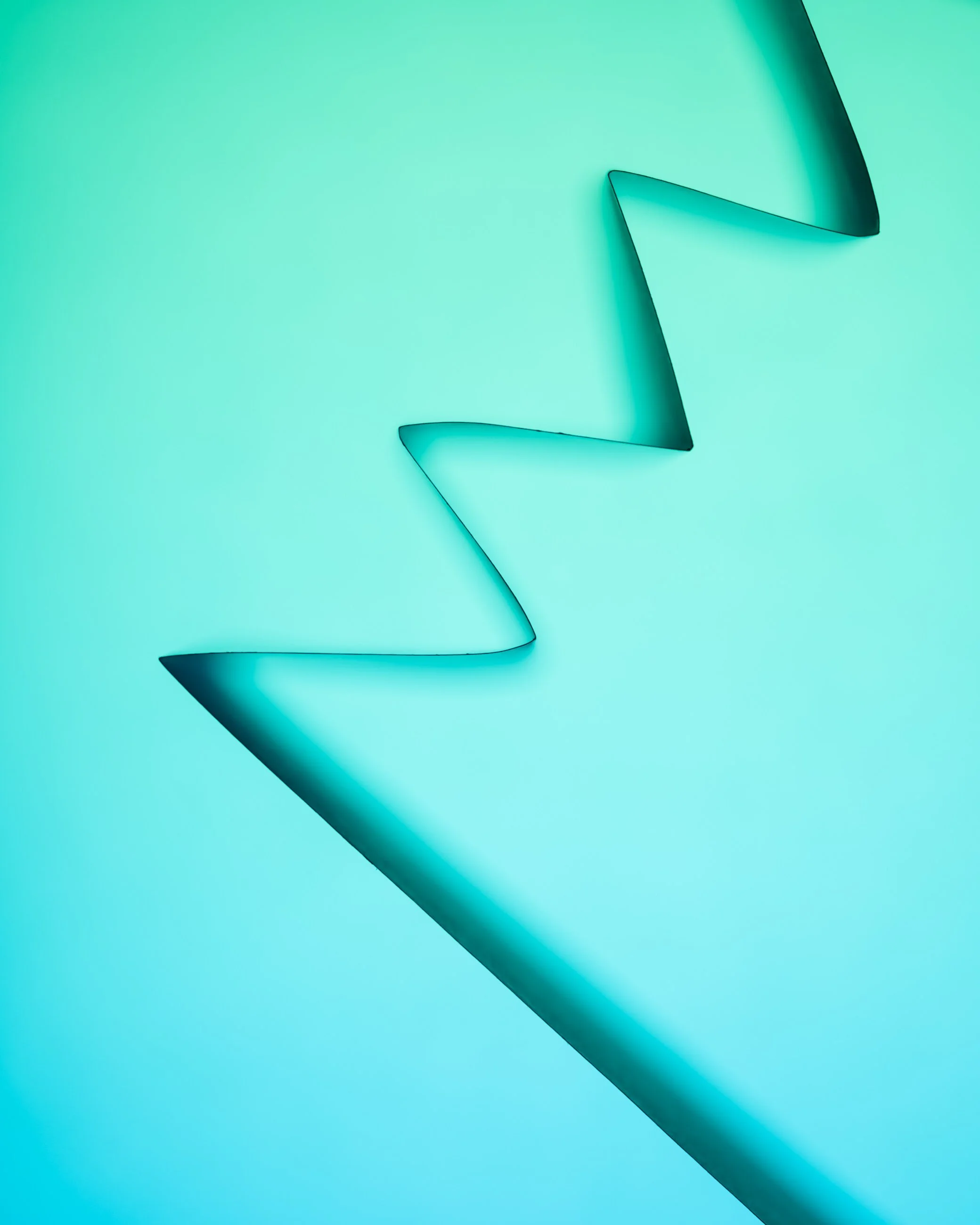 Close-up of a zigzagging tab on a teal background, possibly a piece of paper or plastic.