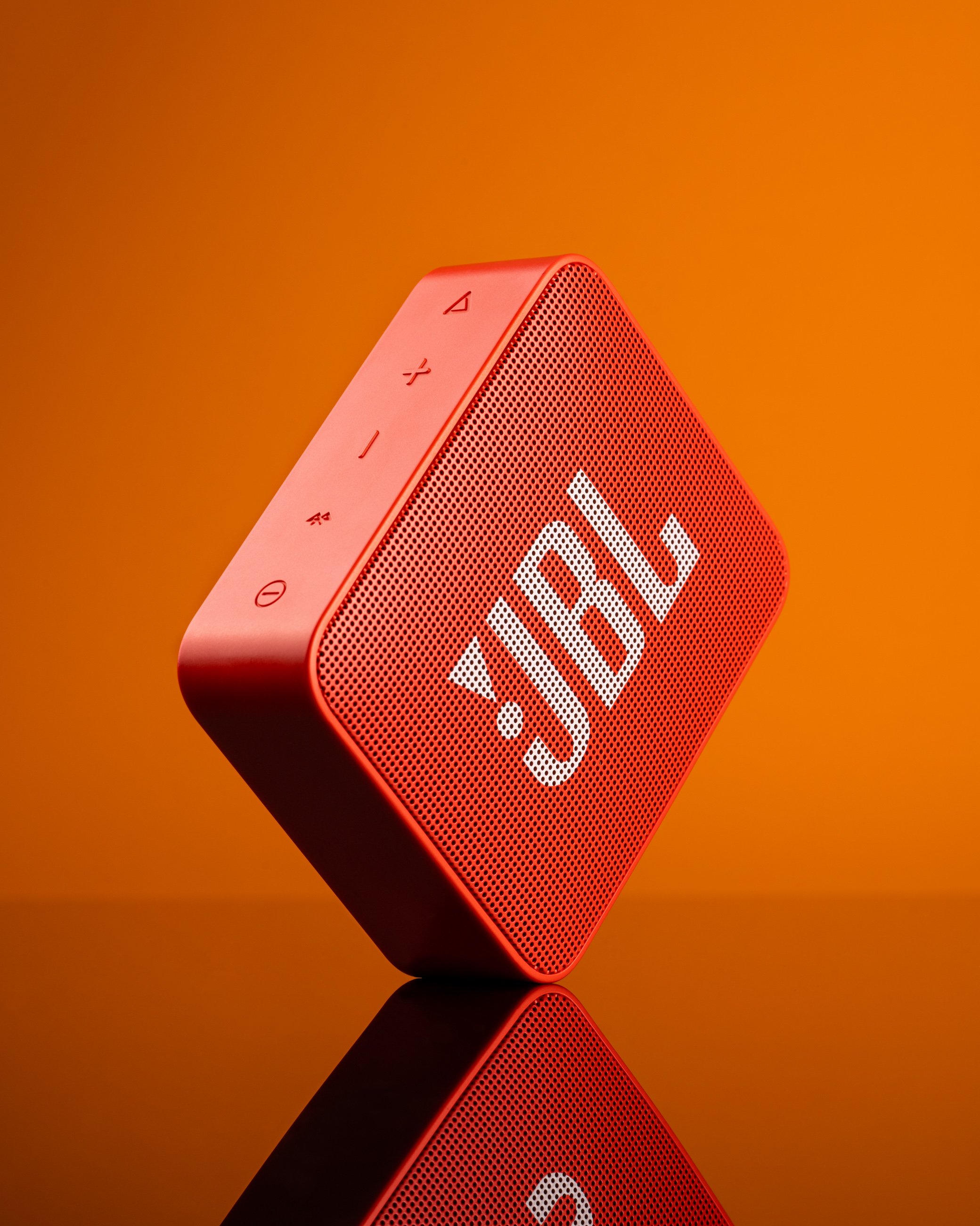 Orange JBL Bluetooth speaker product photography on orange background with reflection