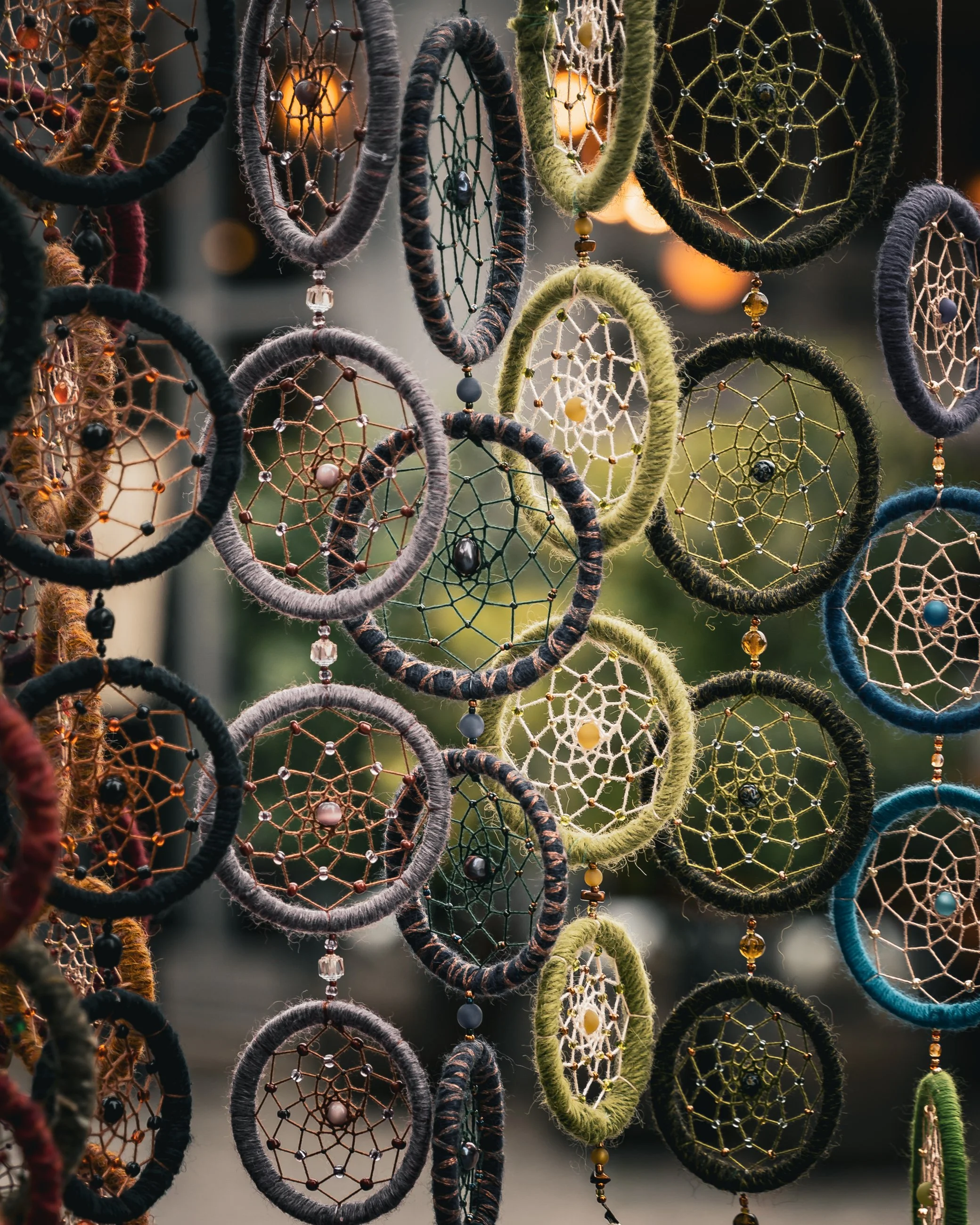 Colorful dreamcatchers with intricate web designs hanging outdoors.