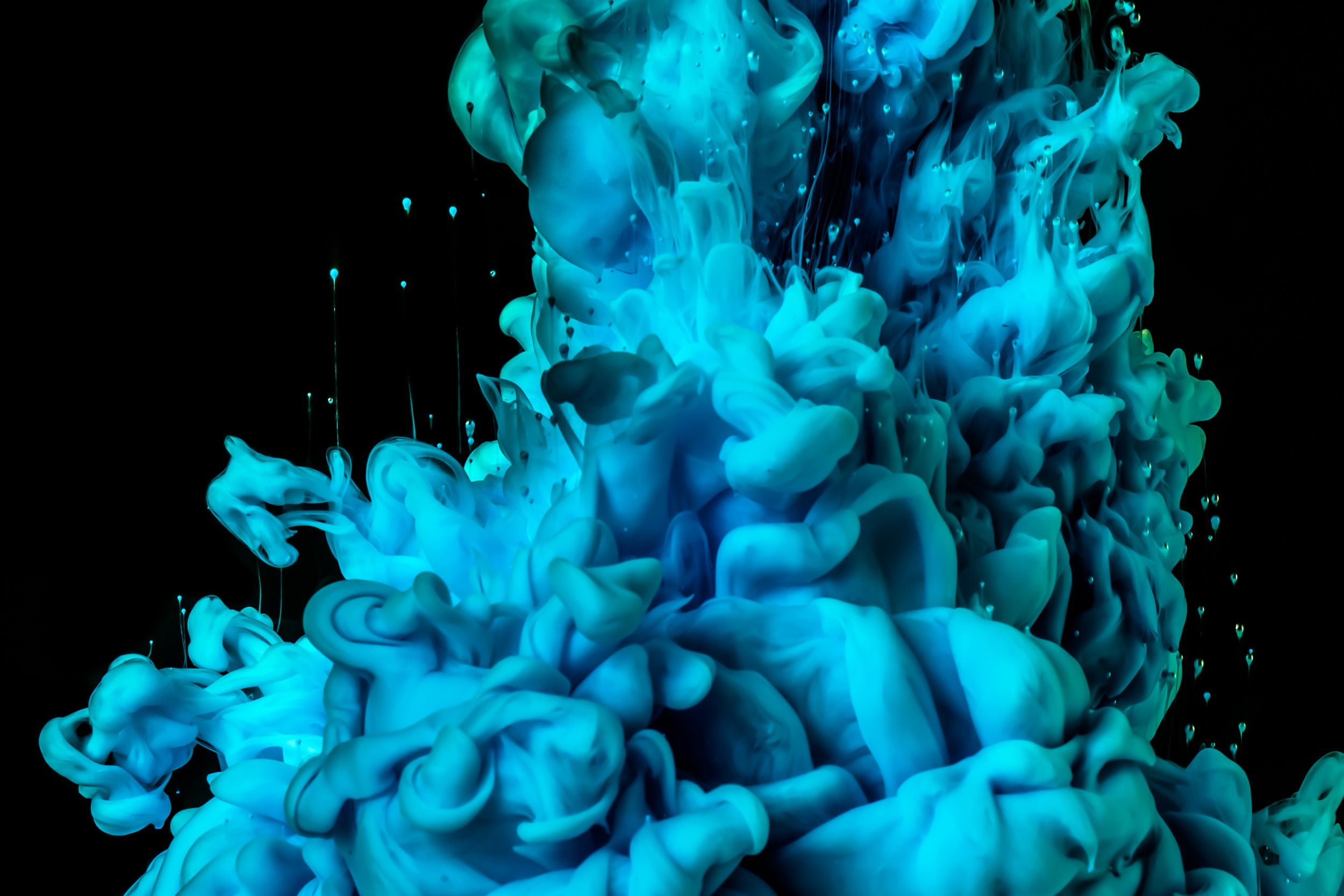 Blue and cyan ink swirling in black water, creating abstract, cloud-like formations.