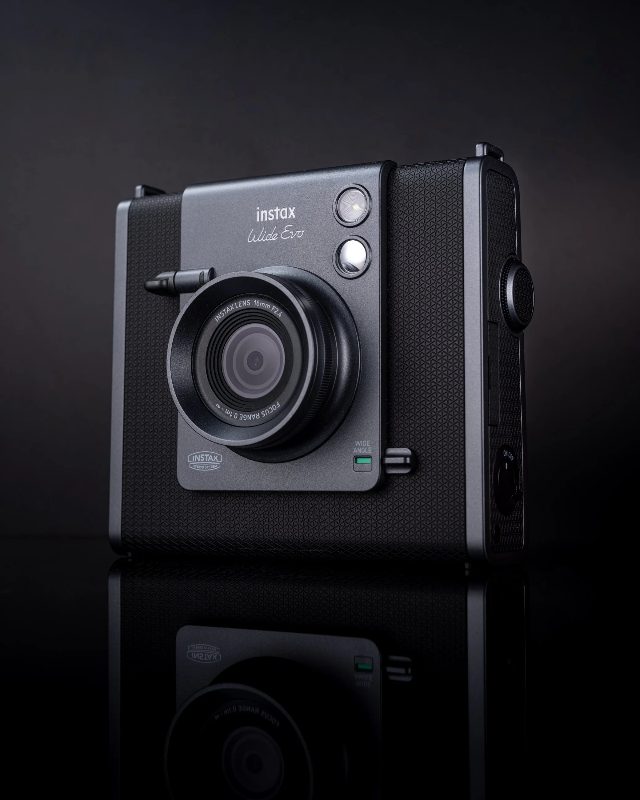 Compact instax evo camera product photography on reflective surface with dramatic dark lighting