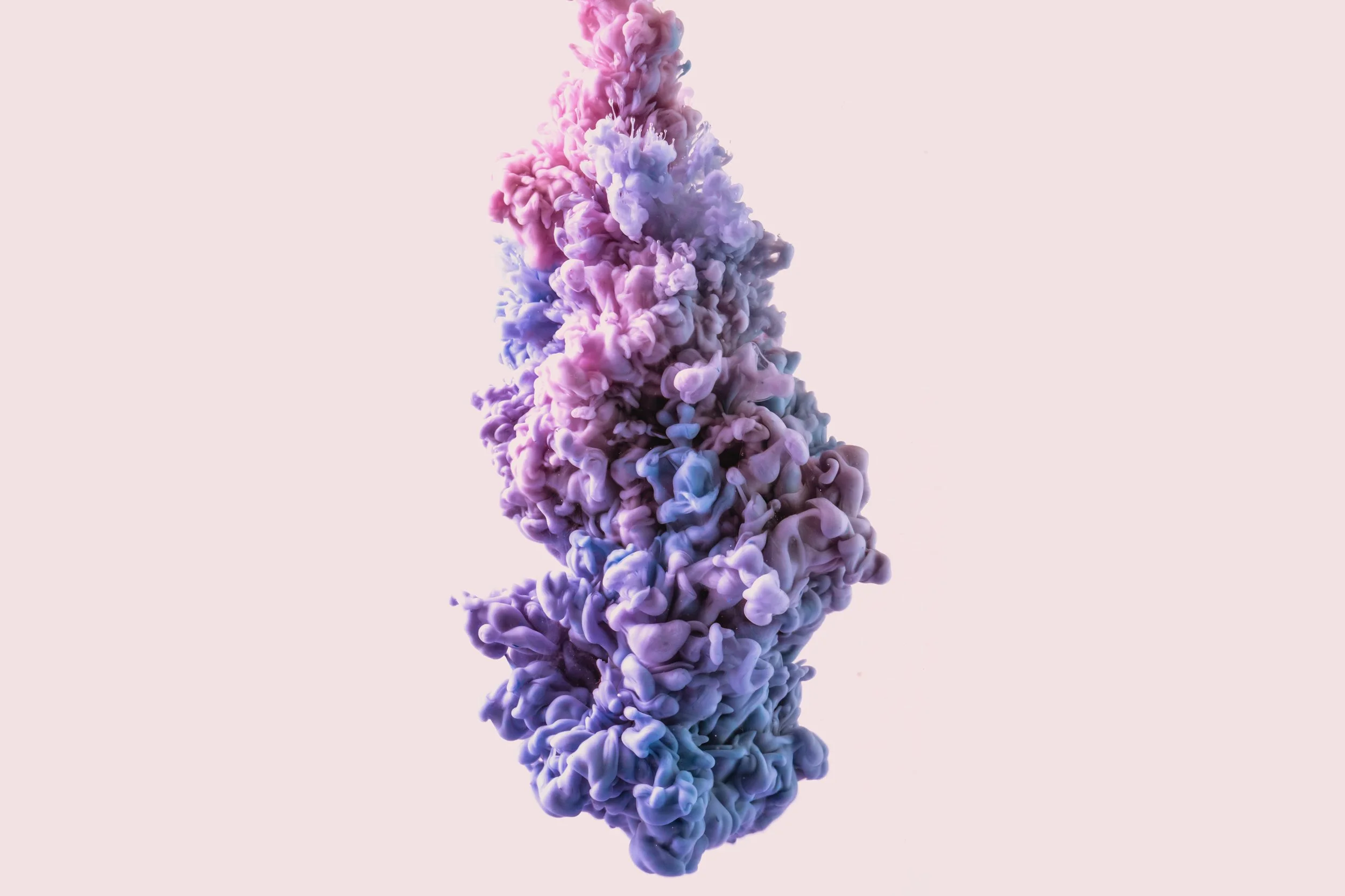 Colorful cloud of purple, pink, and blue smoke or ink swirling against a light pink background.