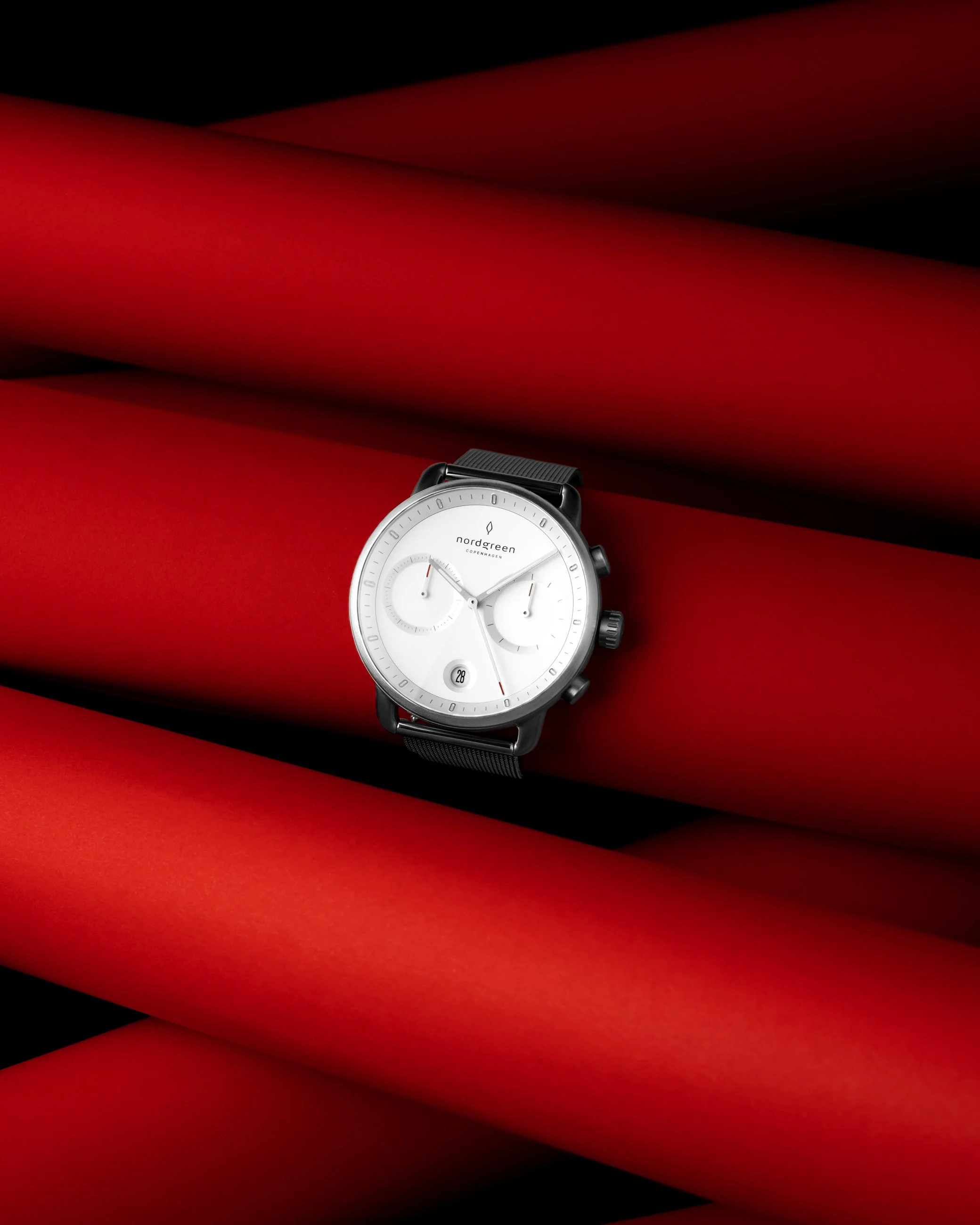 Nordgreen wristwatch product photography on red geometric background with studio lighting