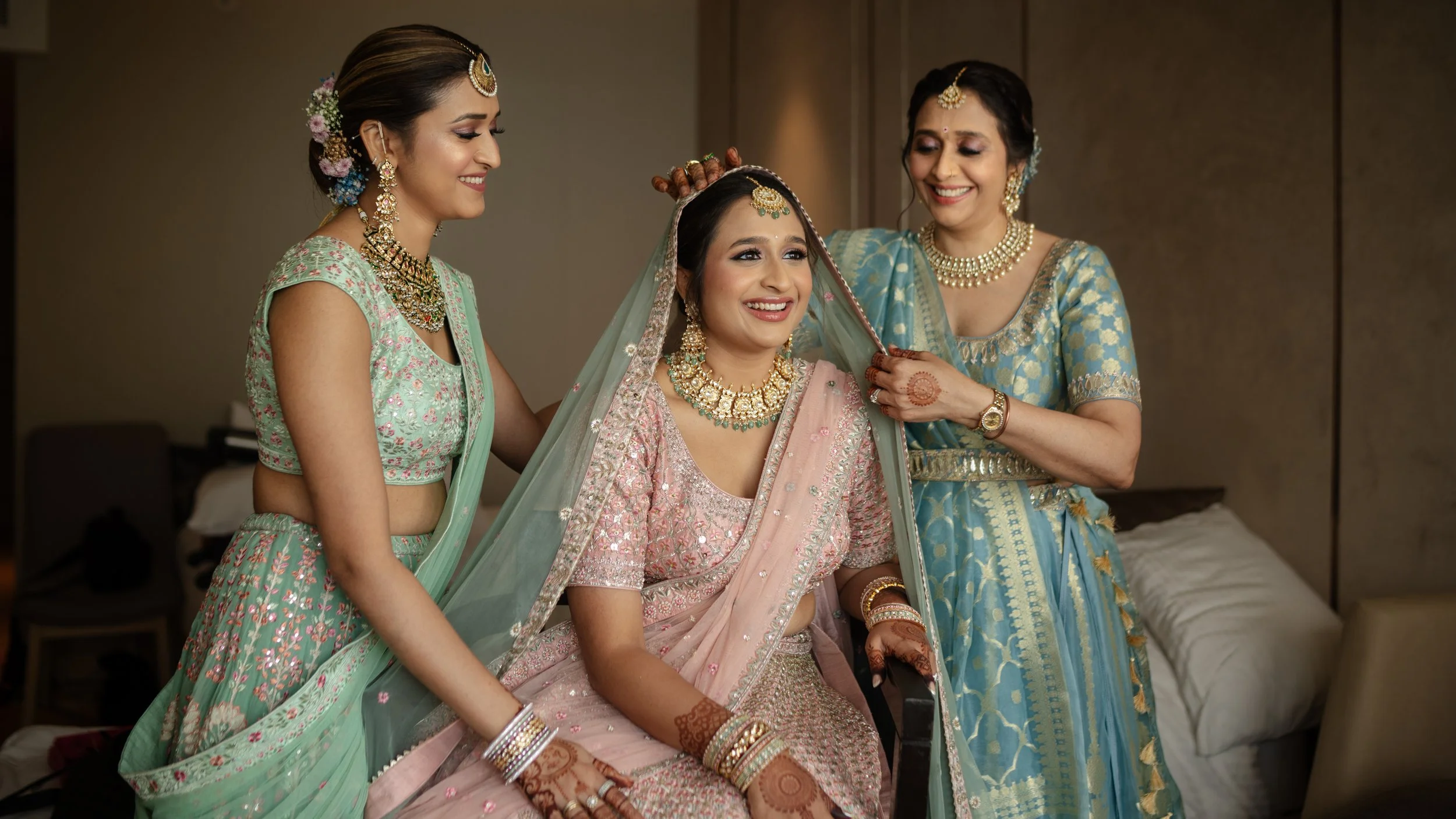 Women in traditional Indian attire preparing the bride for a wedding