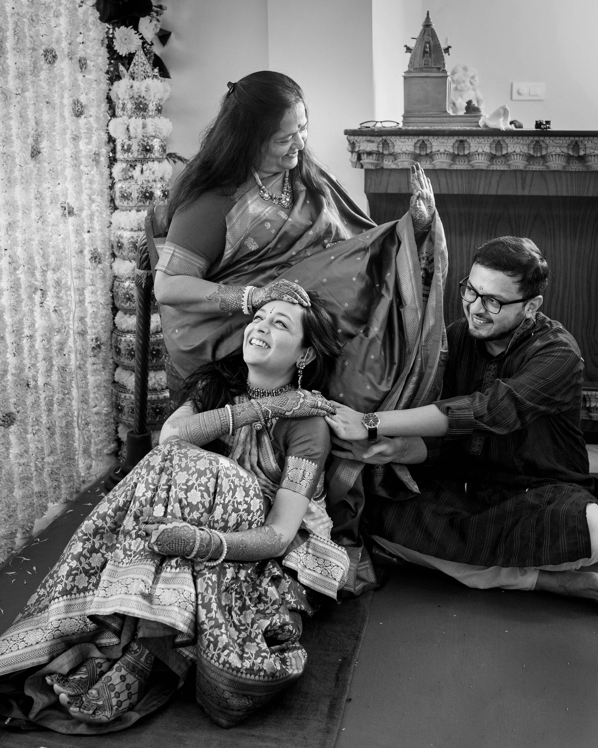 A multi-generational family celebrating a traditional Indian ceremony, with women dressed in sarees and jewelry, family members smiling and showing affection.