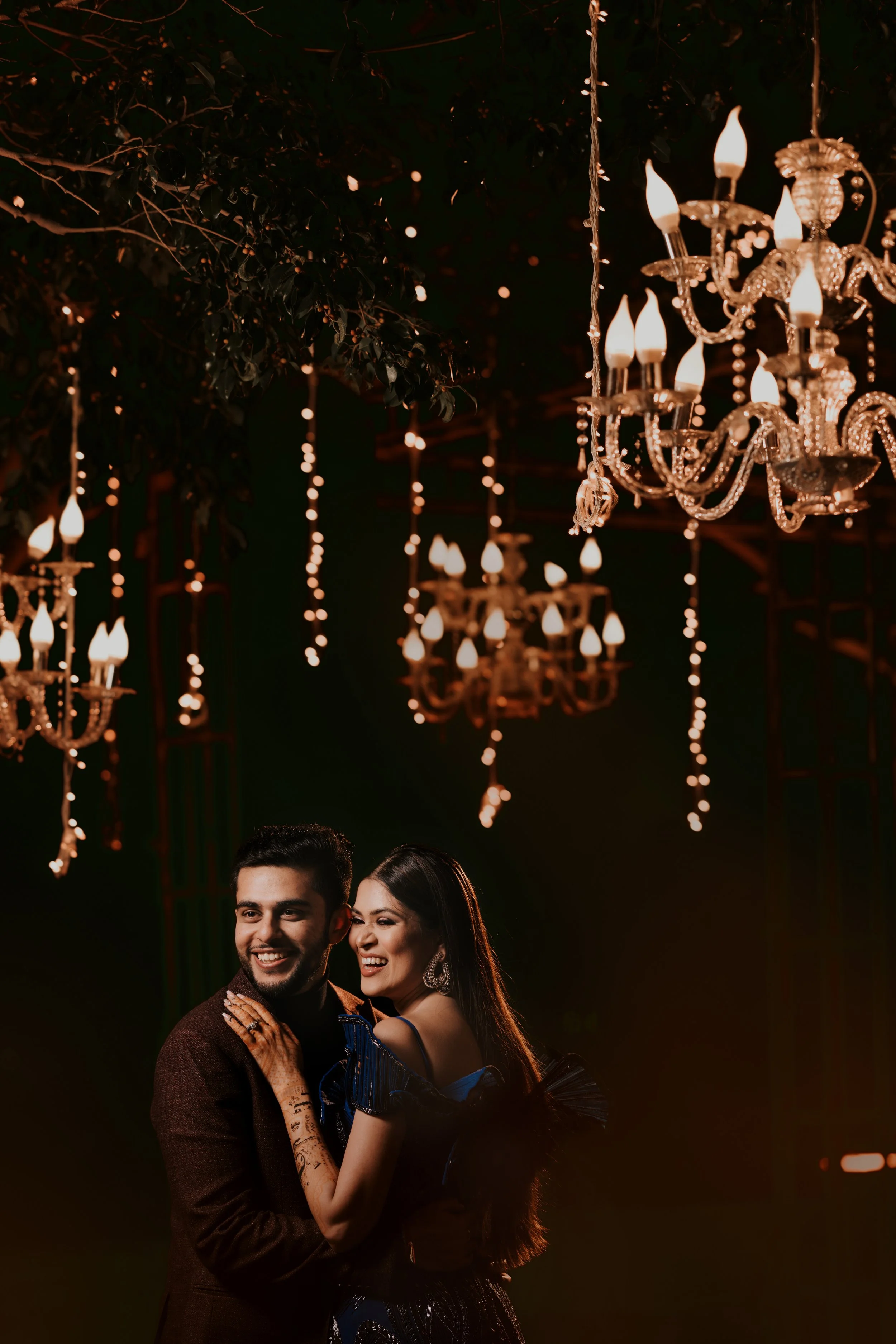 A couple dancing at a fancy event with chandeliers and hanging lights in the background.