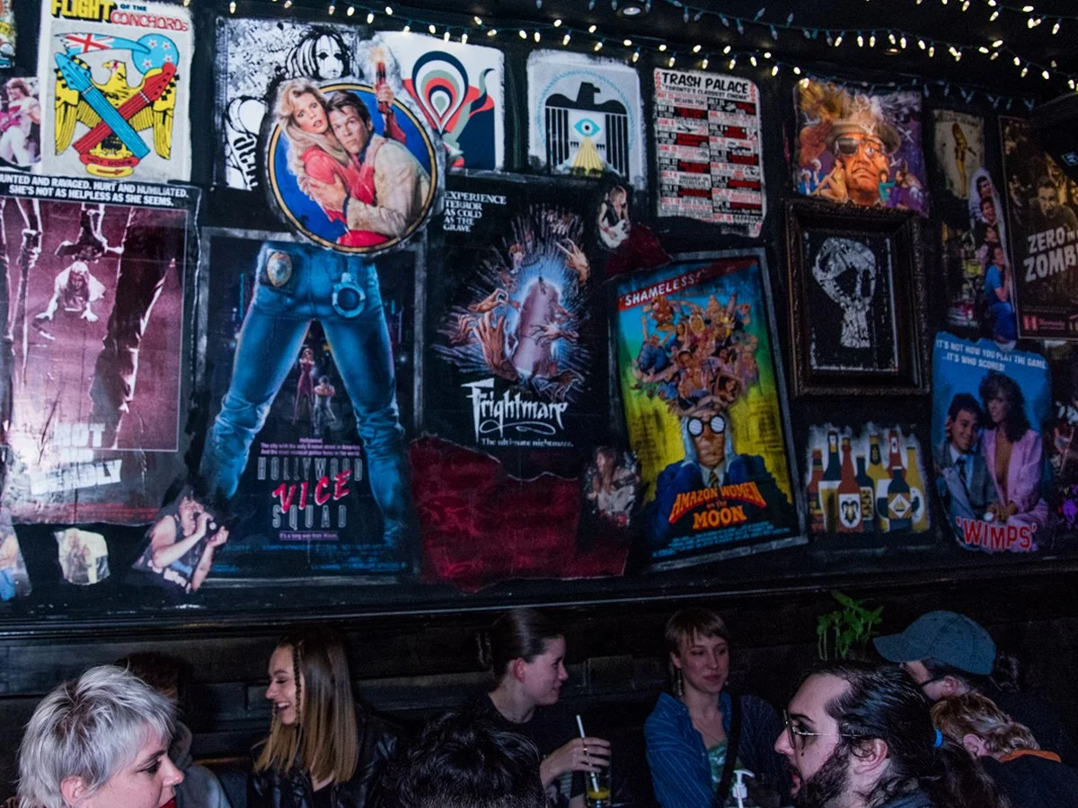A mural with various vintage and pop culture posters on a wall, including movie posters, artwork, and advertisements. 