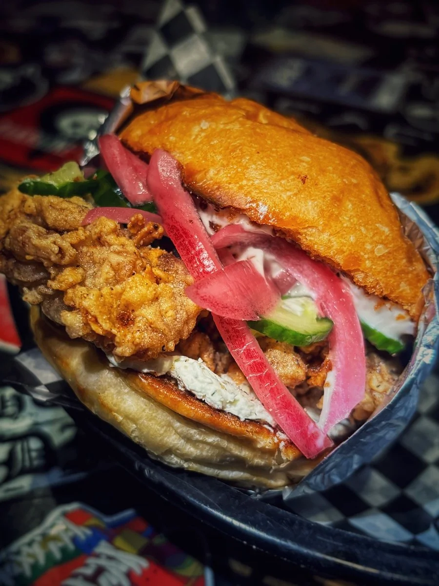 Fried chicken sandwich with pickles, sliced red onions, and cream cheese in a toasted bun