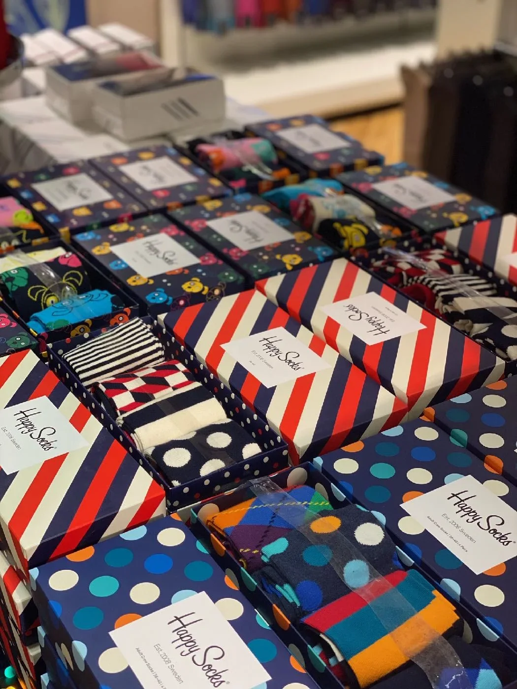 Display of colorful socks in decorative boxes labeled "Happy Socks" at a store.