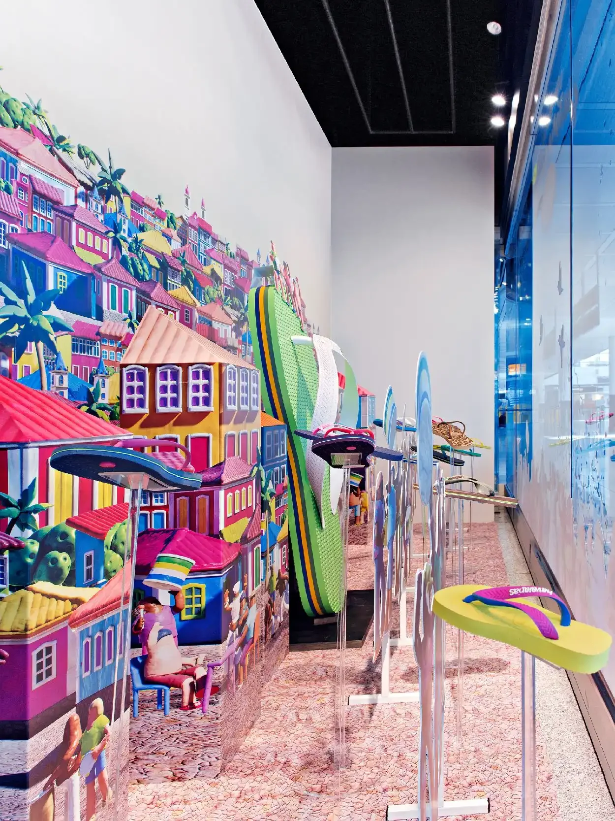 Display of colorful surfboards and wall mural with a vibrant neighborhood scene, inside a modern retail store.