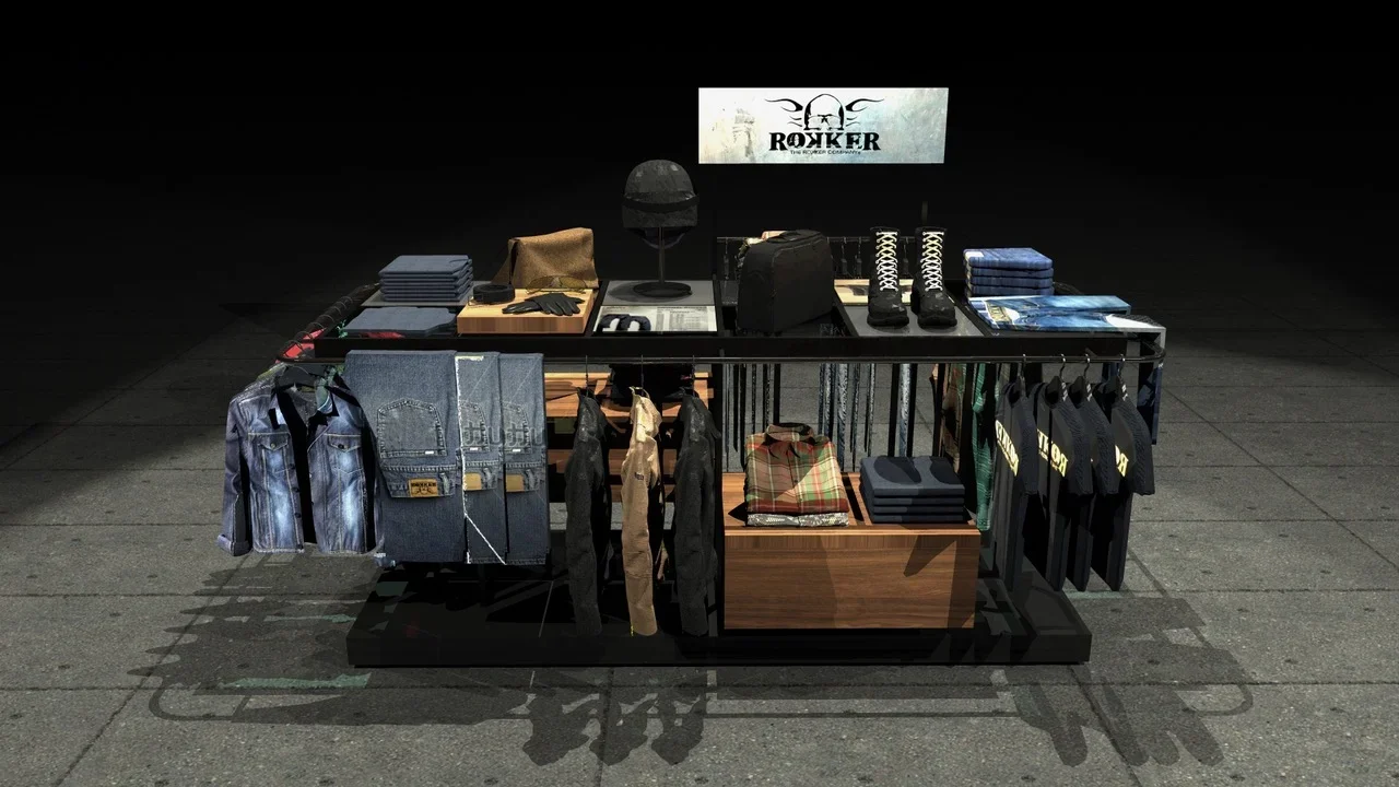 Clothing and accessories display table with jackets, jeans, shoes, bags, and promotional materials, under a sign reading 'Rocker'.
