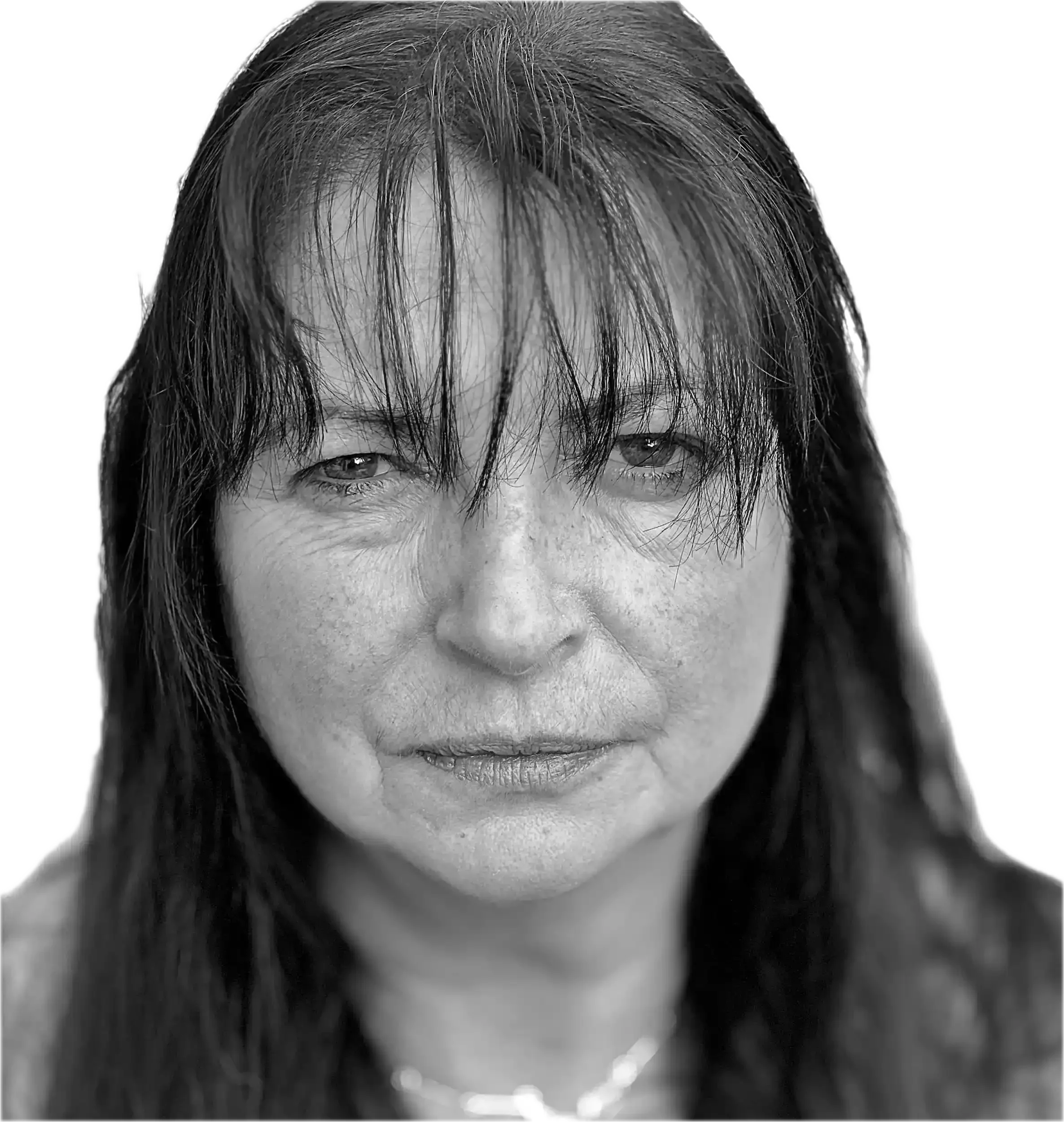 Black and white close-up portrait of a middle-aged woman with long, wet hair, slightly squinting eyes, and a subtle smile, against a black background.