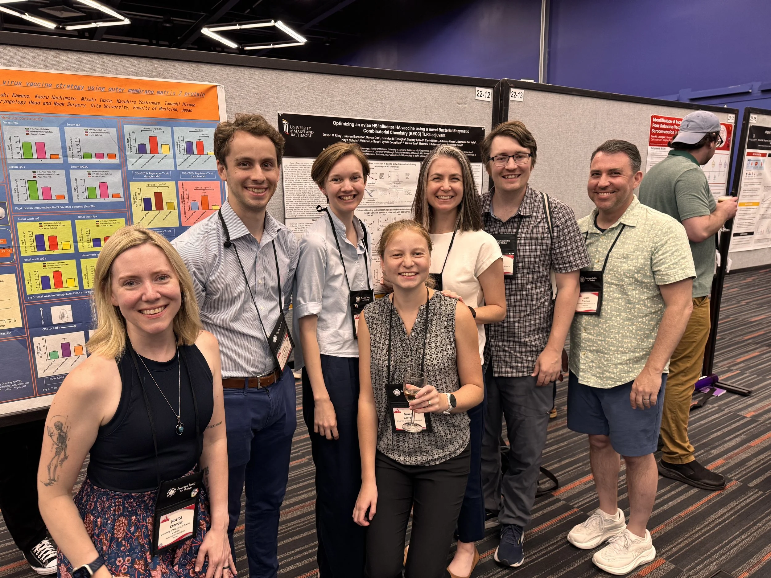 Group of scientists and researchers posing in front of research posters at a conference in a large indoor venue.