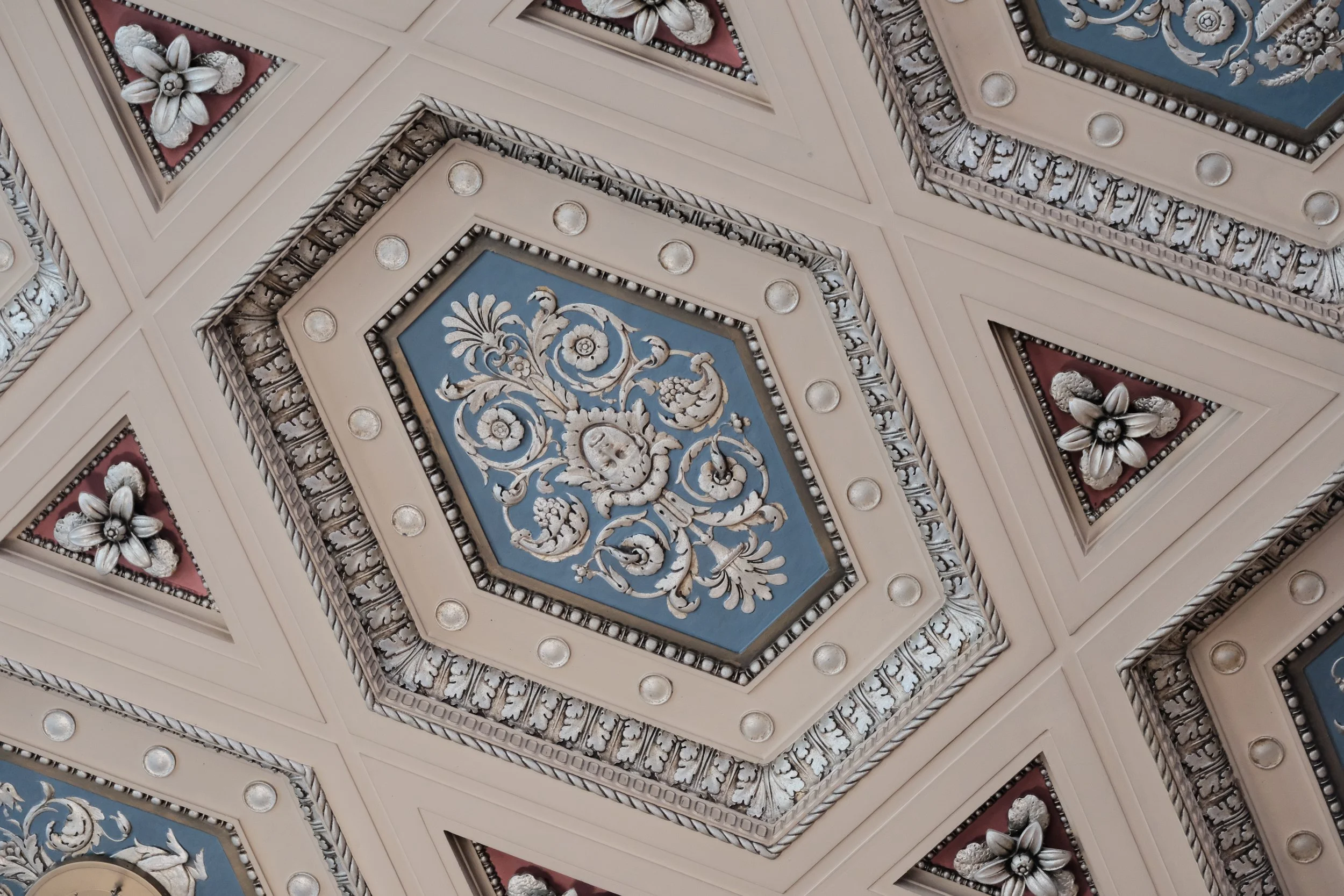 Ceiling with ornate decorative pattern including floral motifs in white, gold, and pastel blue and pink accents.