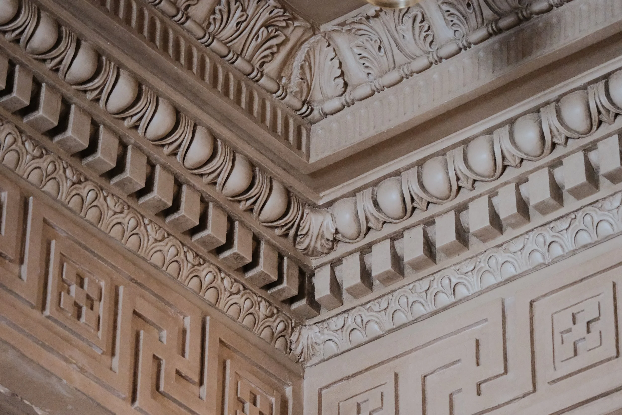 Close-up of ornate architectural ceiling with elaborate carvings, moldings, and decorative elements.