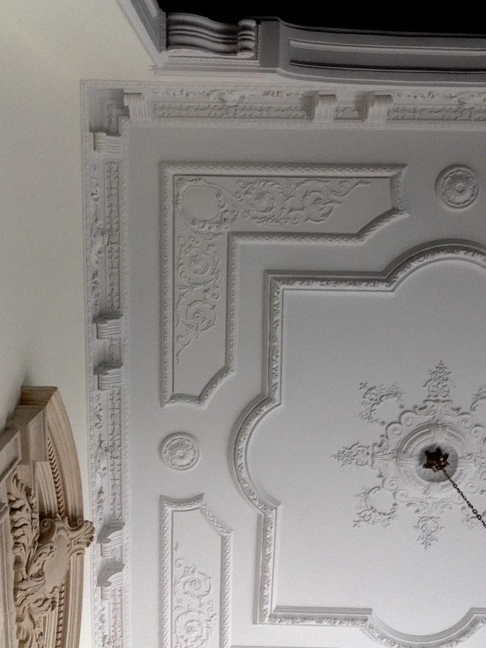 Ornate white ceiling with decorative molding and a central chandelier fixture.