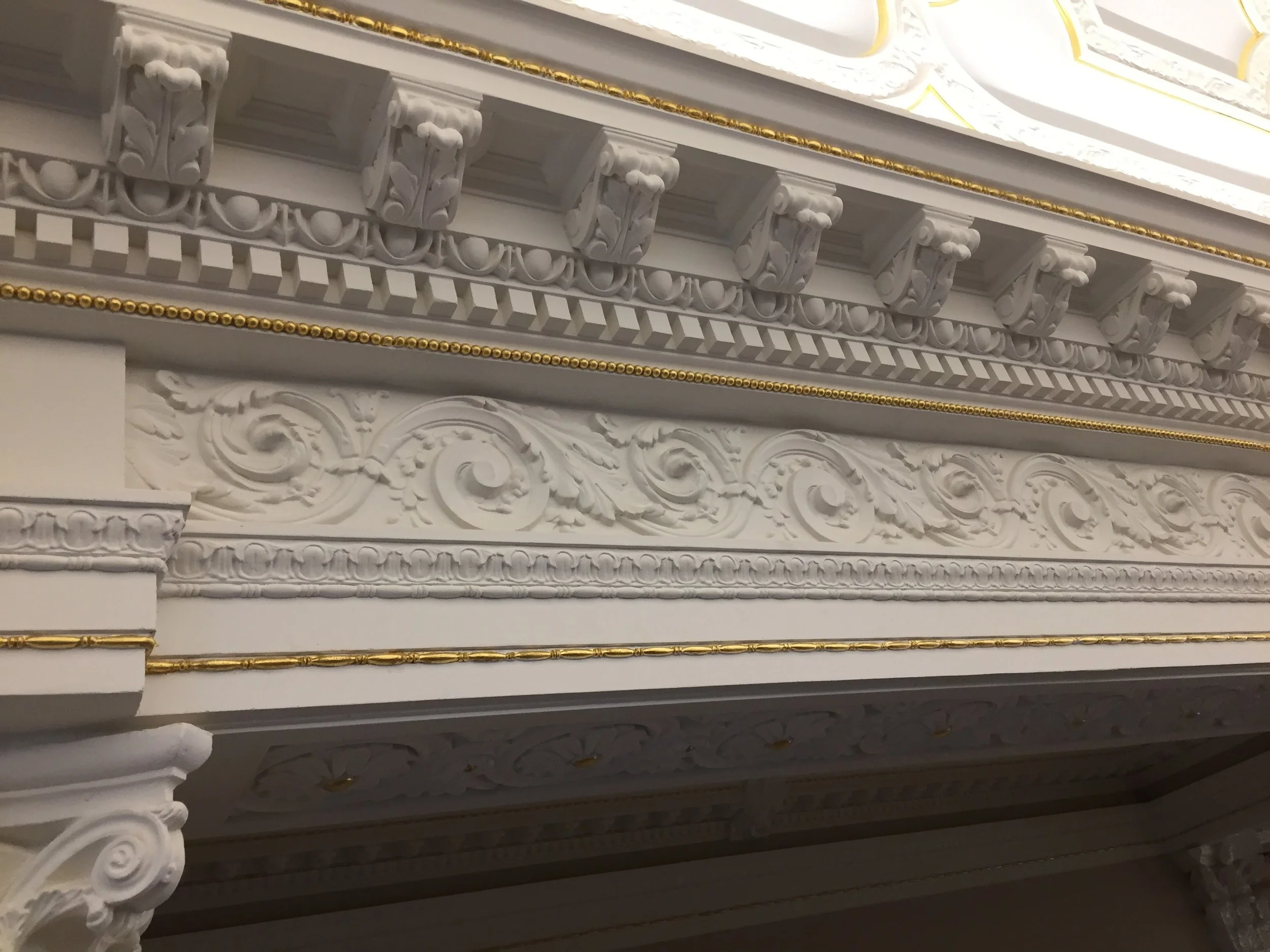 Decorative ornate ceiling molding with white and gold accents.