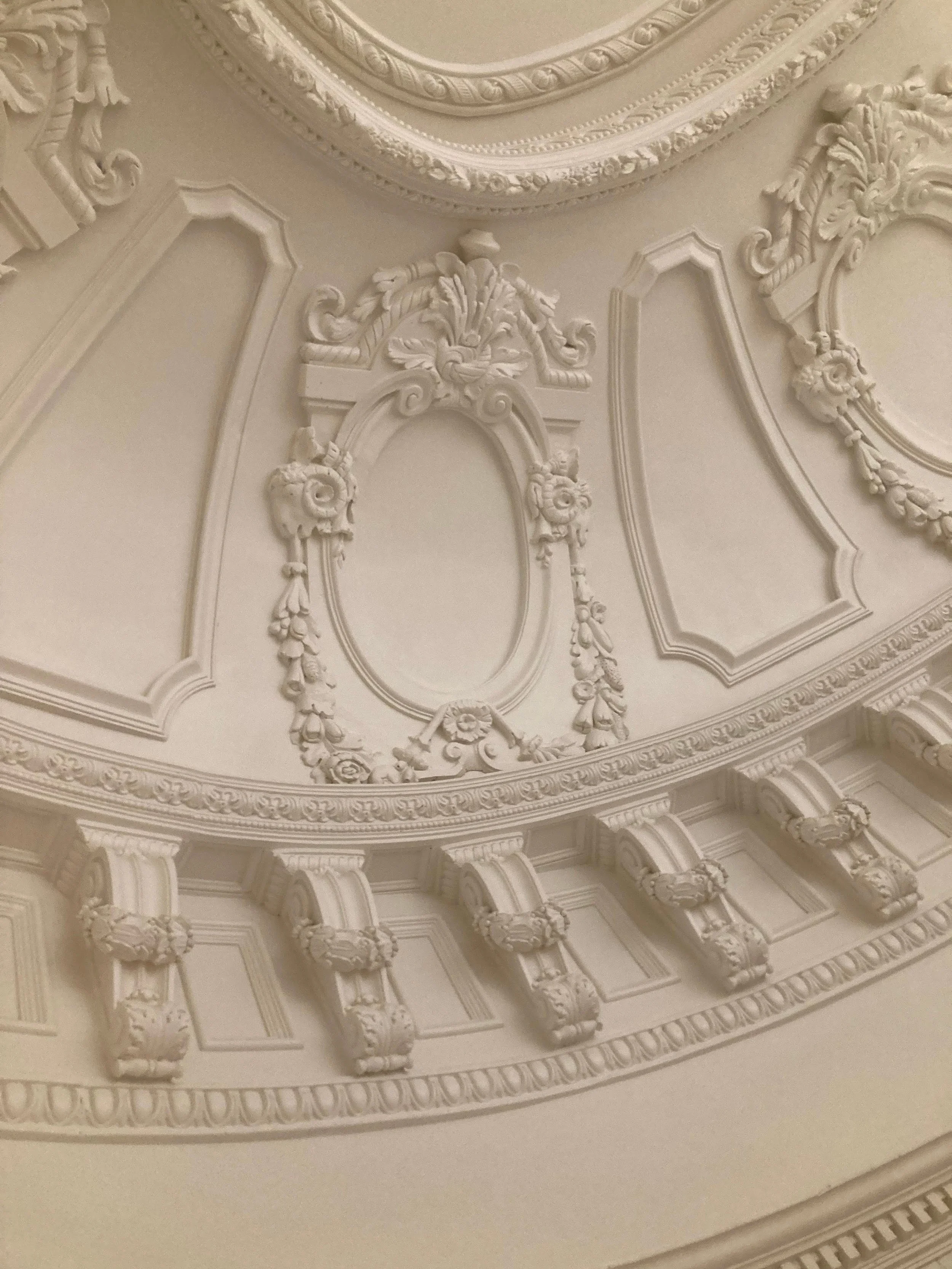 Ornate ceiling with decorative molding, scrolls, and floral motifs in a classical style.
