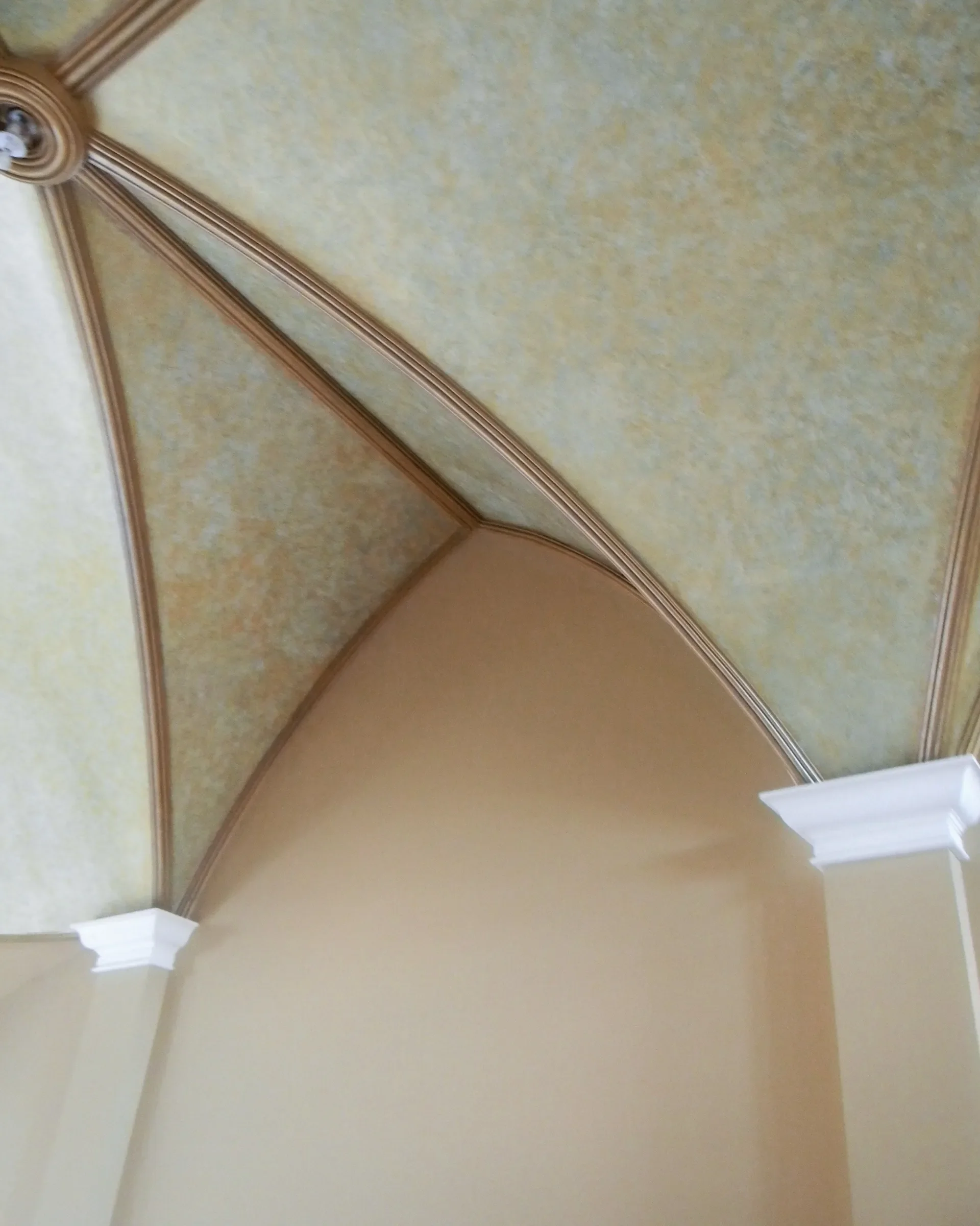 Close-up view of a decorative ceiling with intricate crown molding and an archway.