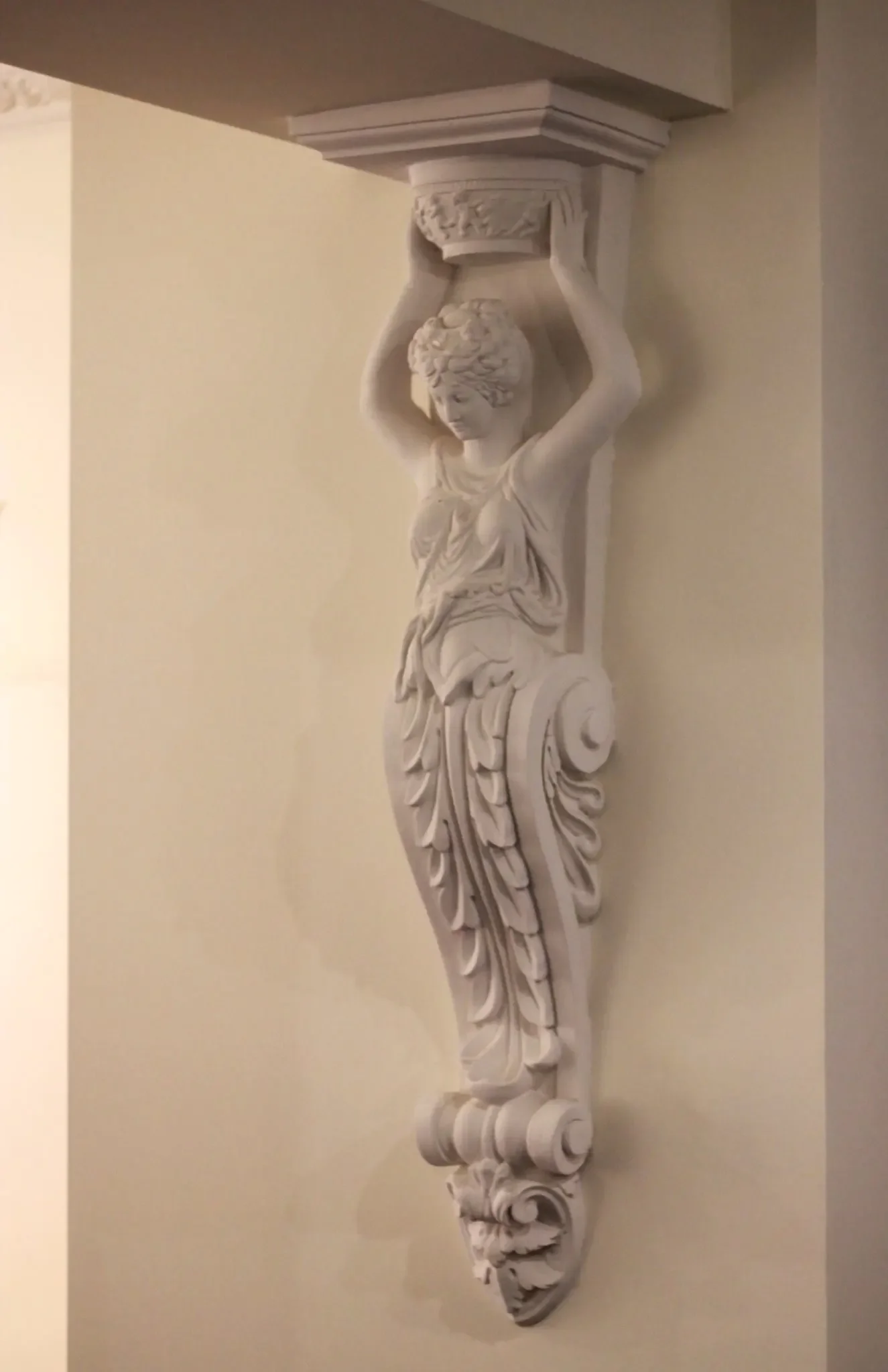 Ornate white decorative wall bracket with a woman figure holding a rectangular platform