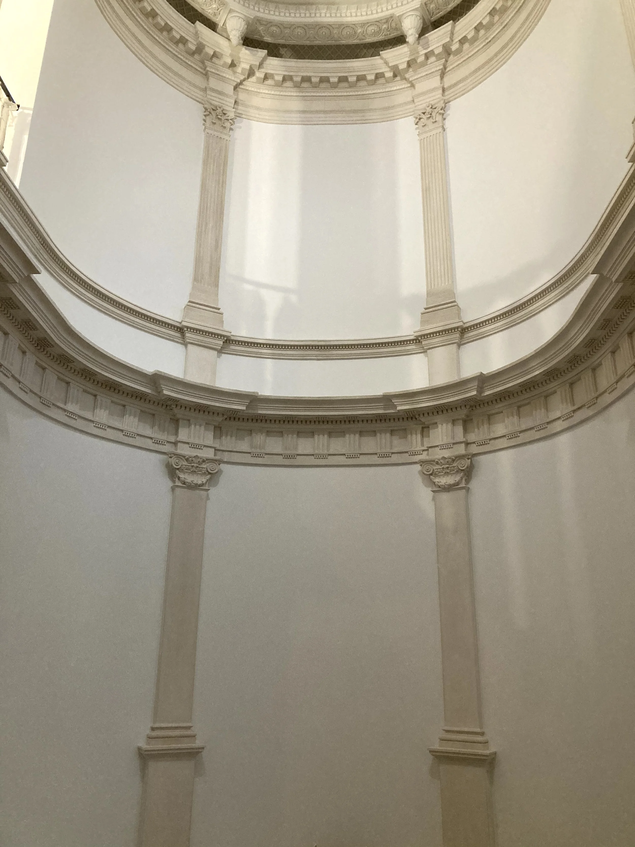 Interior view of a domed ceiling with classical architectural details, including columns, decorative moldings, and a curved balcony.
