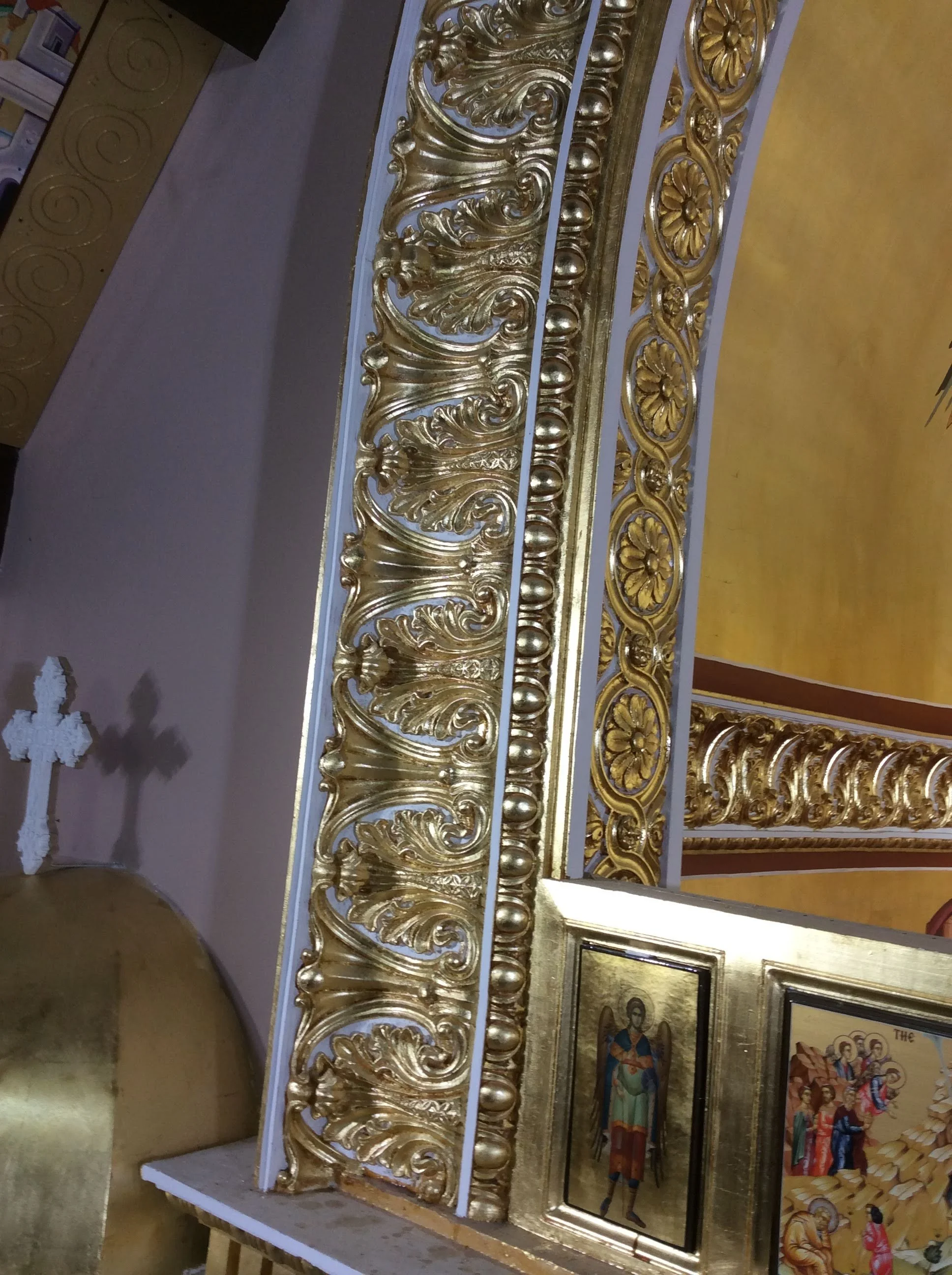 Close-up of ornate gold and silver decorative framing with religious icons and artwork, likely part of an altar or religious display.