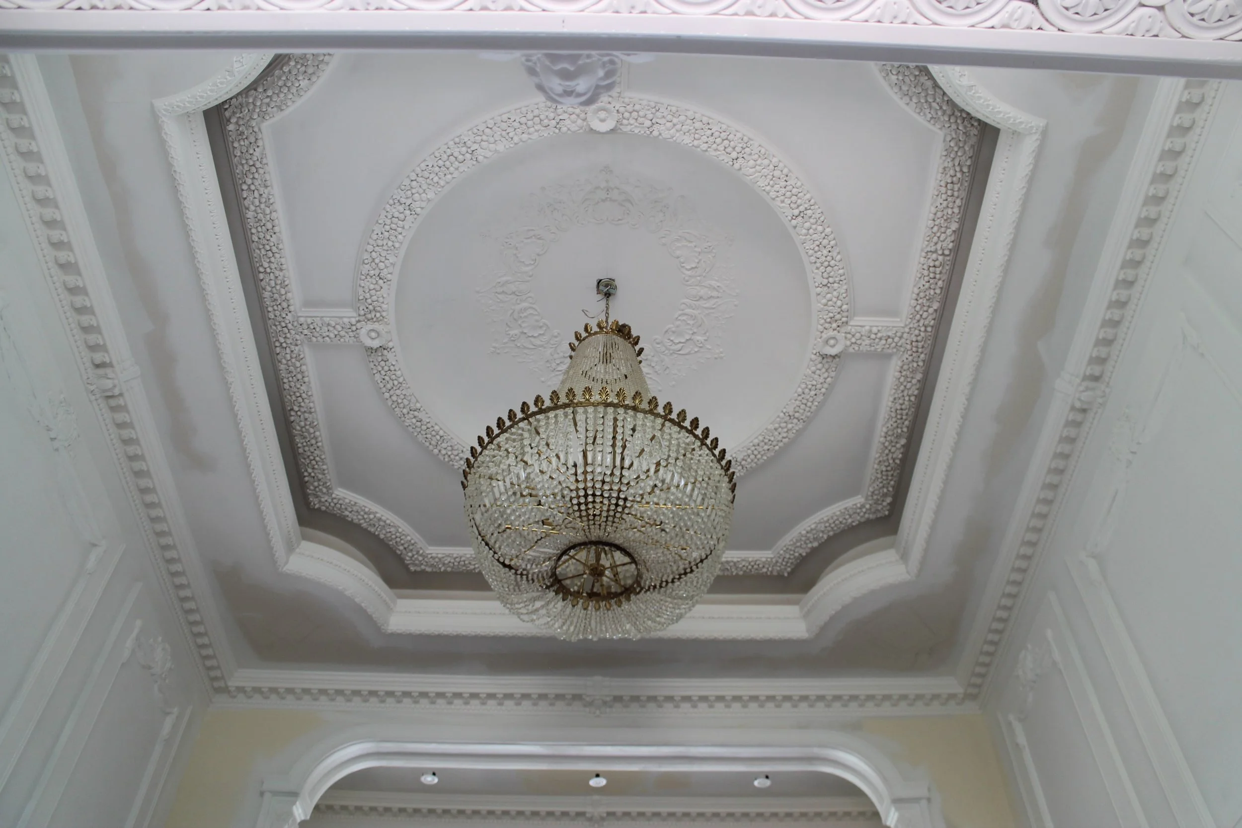 Elegant interior ceiling with intricate molding and a large crystal chandelier.