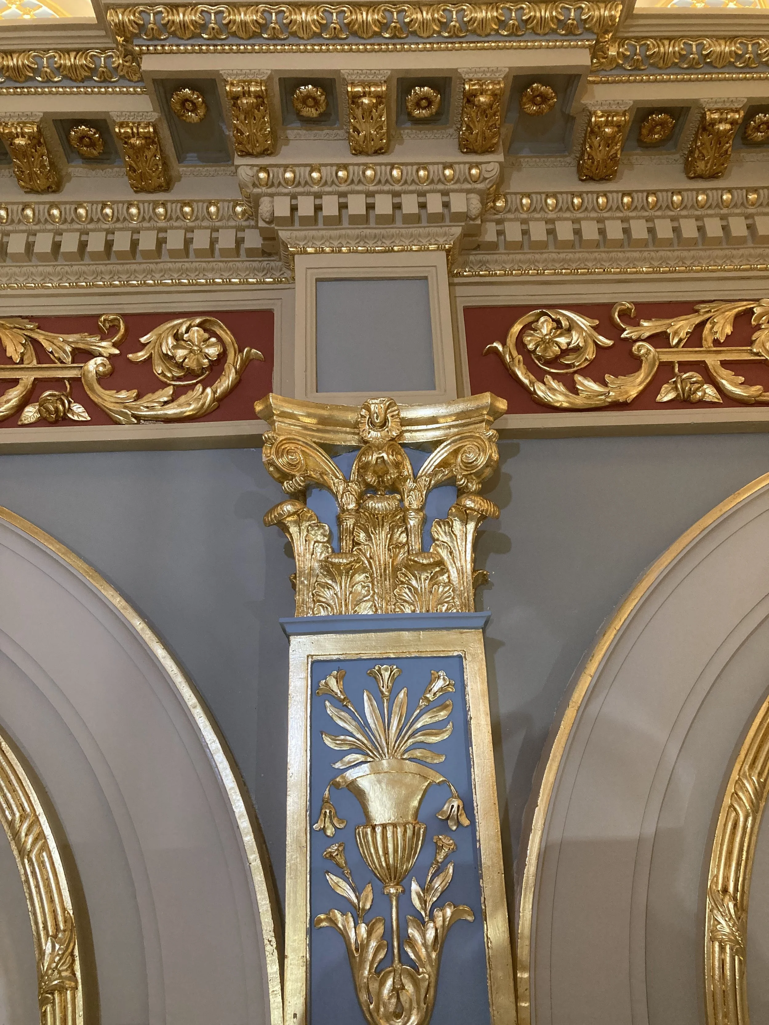 Ornate decorative architectural molding with gold accents on a ceiling and wall