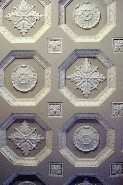 Ceiling tiles with ornate floral and geometric designs arranged in a grid pattern.