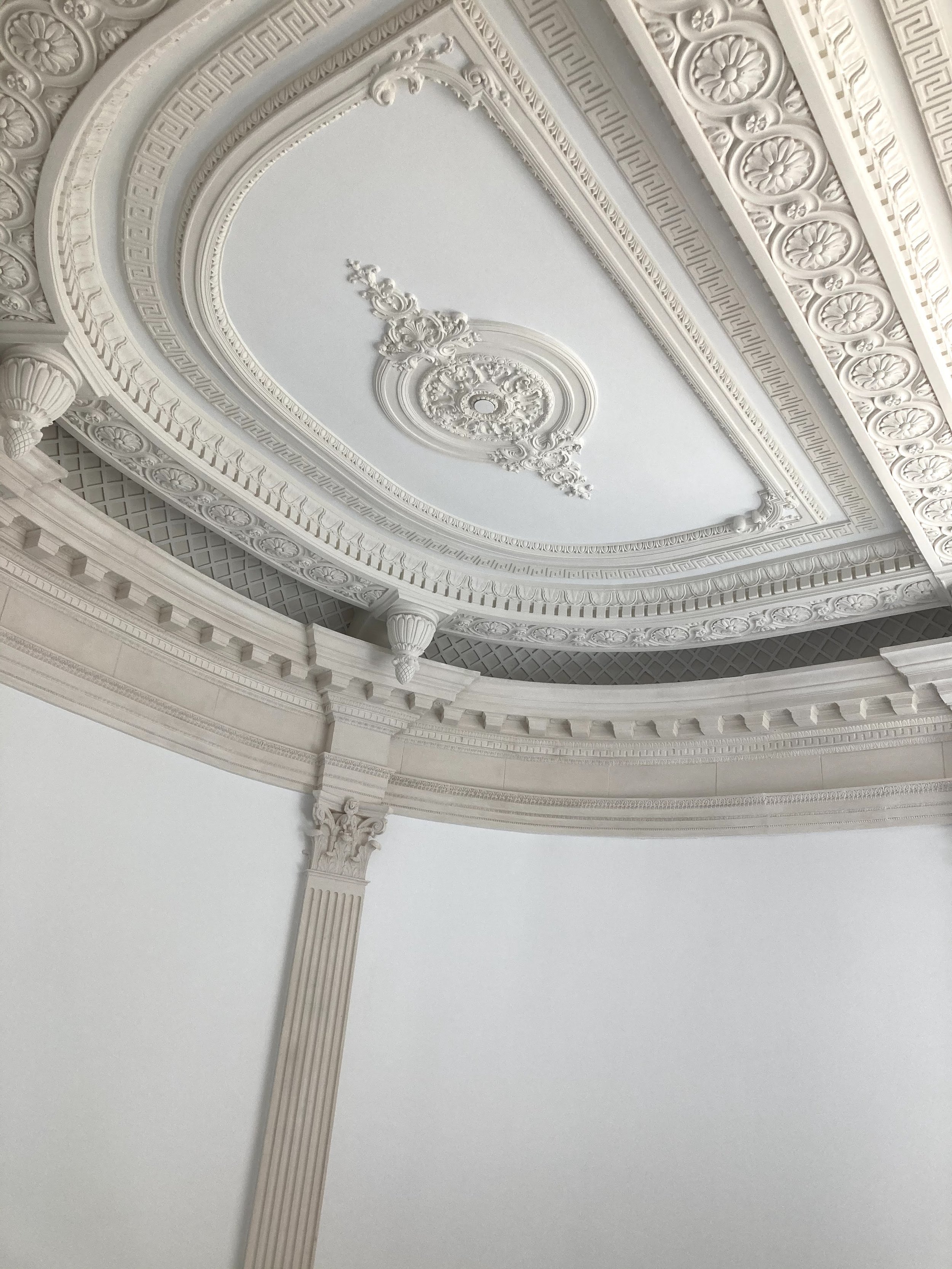 Ornate ceiling with decorative molding, intricate plasterwork, and a central embellishment in a classical style.