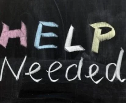 Chalkboard with the words 'HELP Needed' written in colorful chalk.