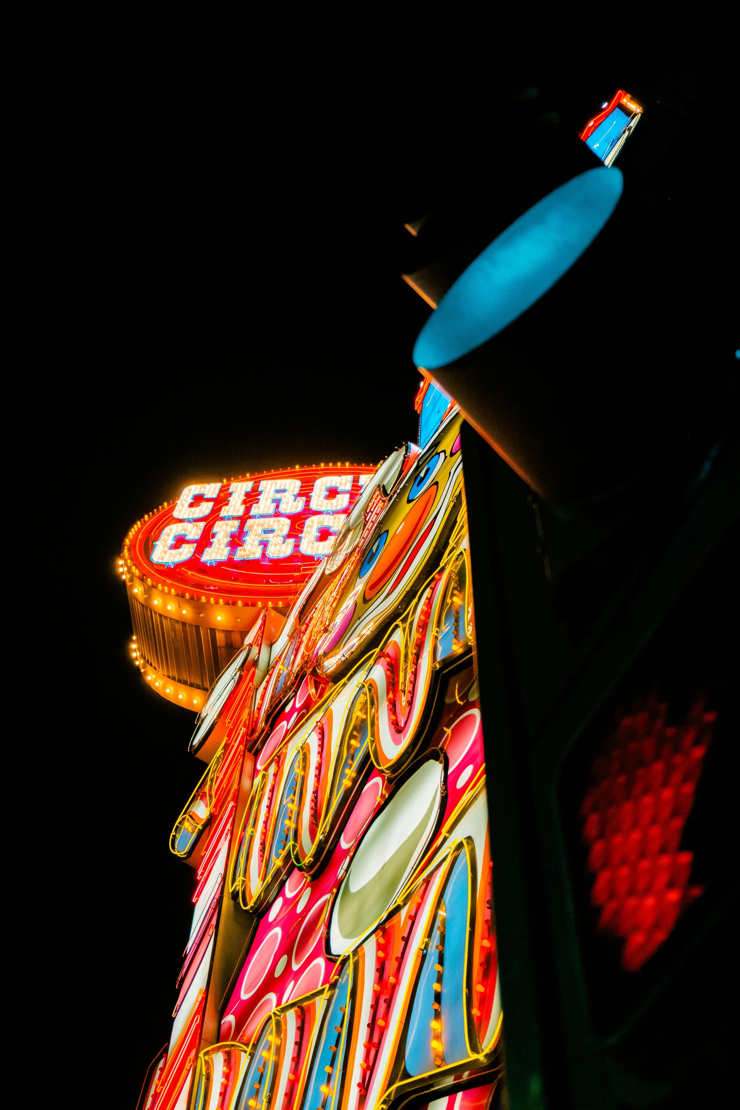 Night view of a brightly lit, colorful casino or entertainment venue sign with neon lights, reading 'CIRCUS CIRCUS' in the background.